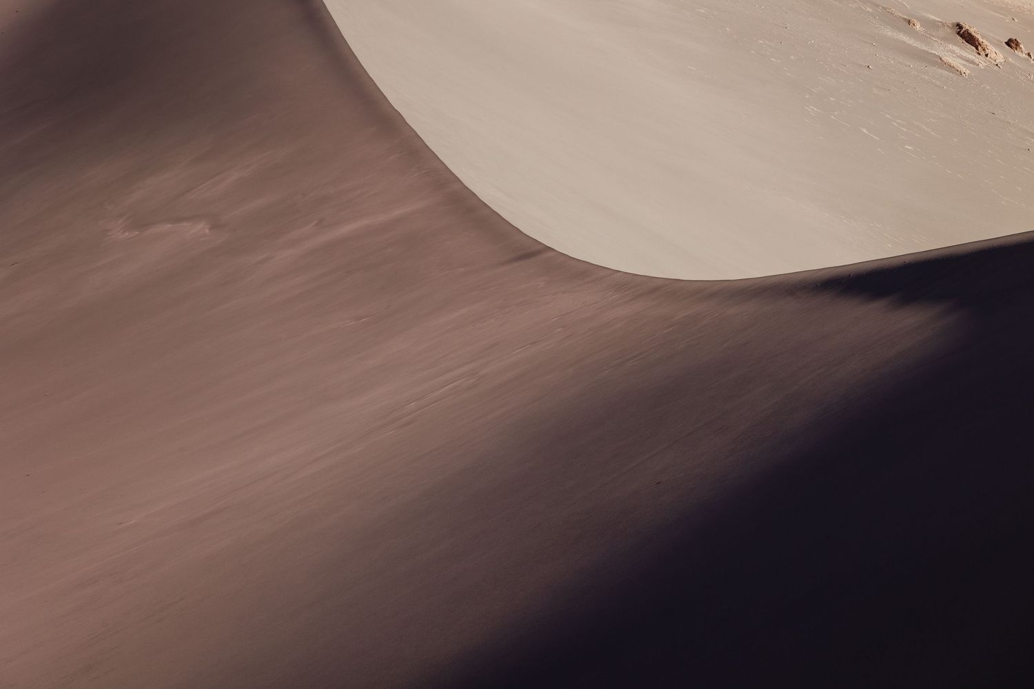 Abstract desert landscape with smooth sand dunes casting dramatic shadows in warm earth tones.