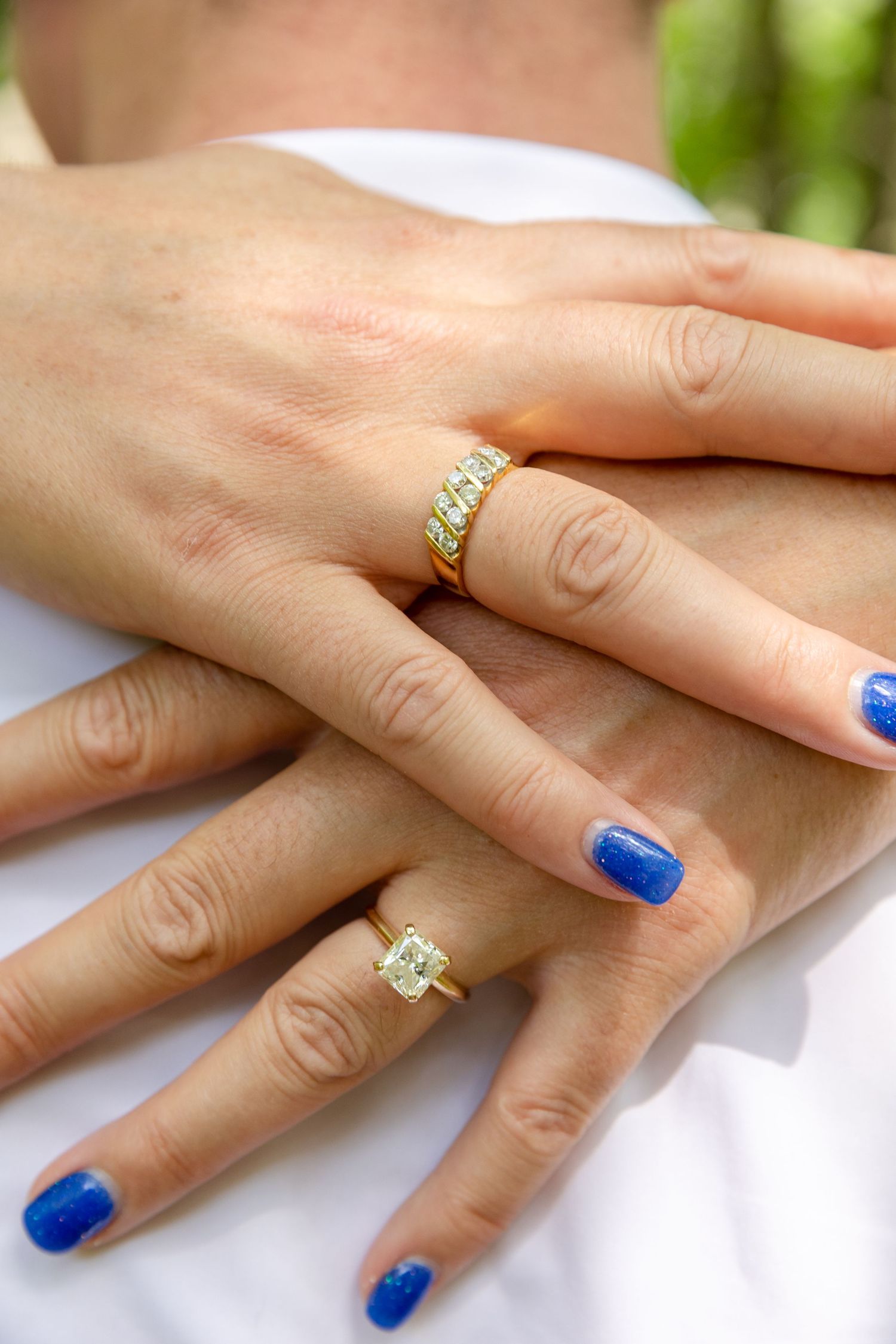 A hand wearing a blue crystal diamond engagement ring shown in multiple angles against a blurred background.