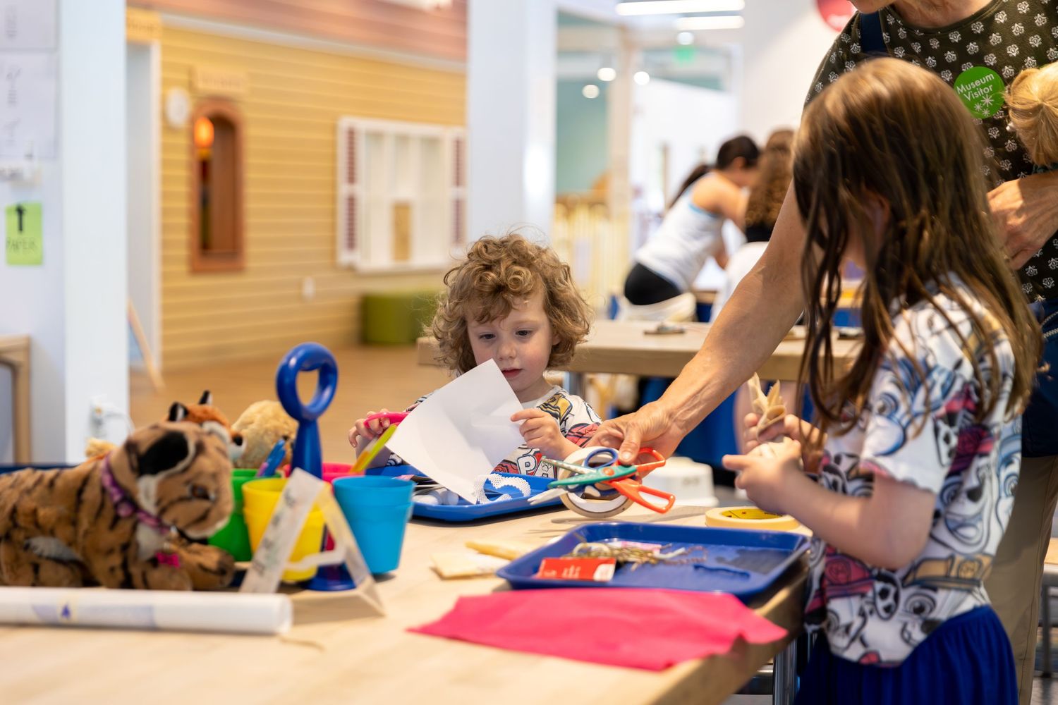 Children engaged in hands-on learning activities at various classroom stations with educational toys and materials.