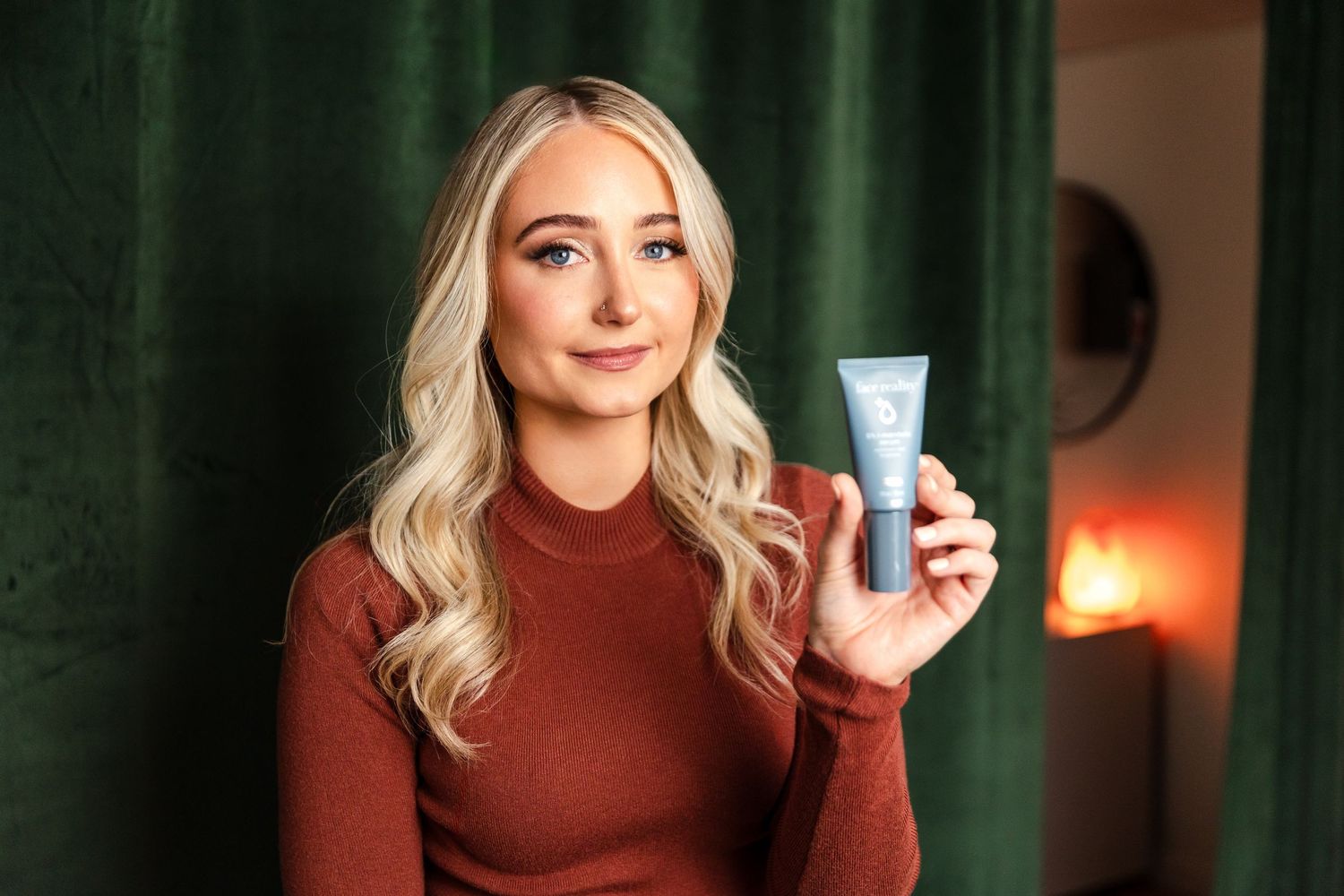 Person in red turtleneck poses for lifestyle photos in a dimly lit room with fall-inspired decor.