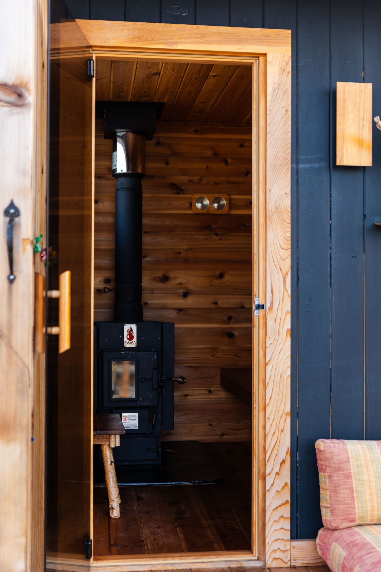 Interior of modern cabin with black walls, natural wood trim, and built-in storage showing a minimalist design aesthetic.