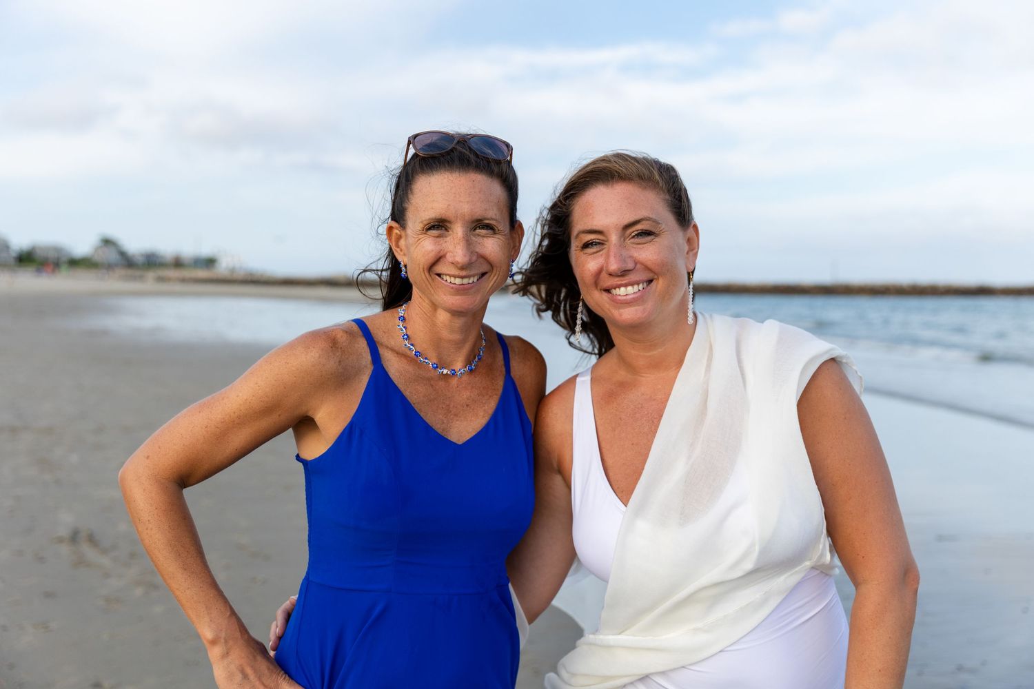 Two friends embrace while walking together on a scenic beach during sunset or sunrise.