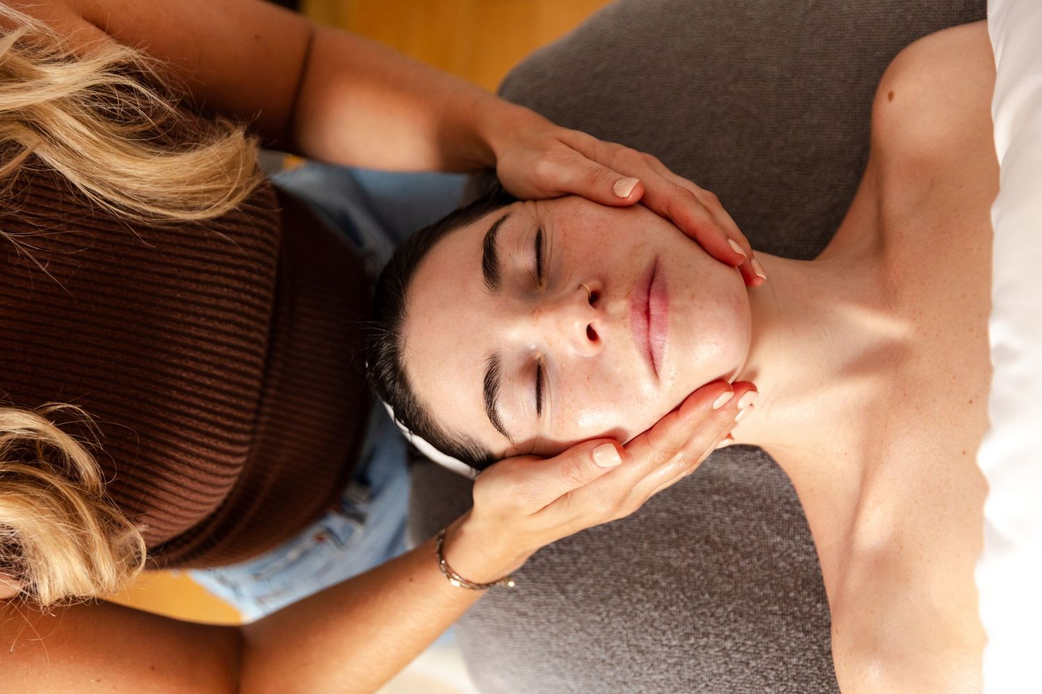 Someone receiving a relaxing facial massage treatment while lying on a spa table.
