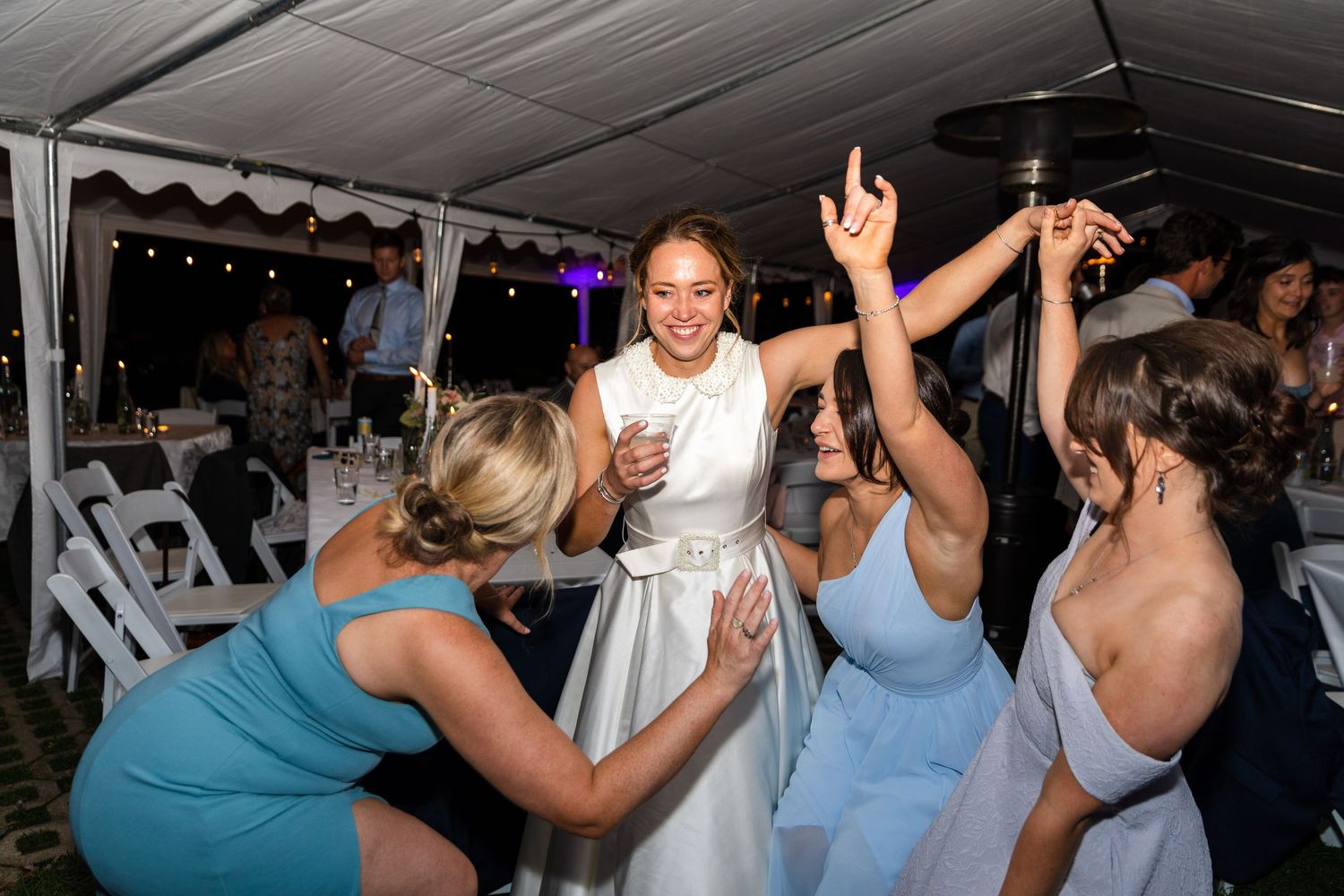 People dancing and having fun at a lively party celebration inside a venue with festive lighting and decor.