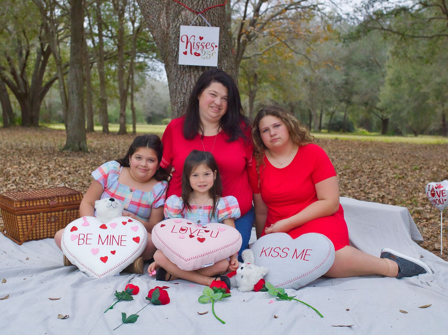 A family group poses on a blanket with Valentine's Day themed pillows.