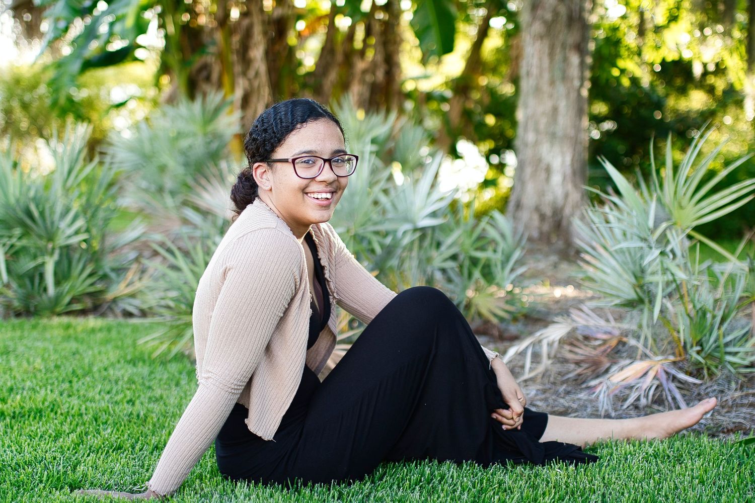Person in casual attire relaxing on grass in garden setting.