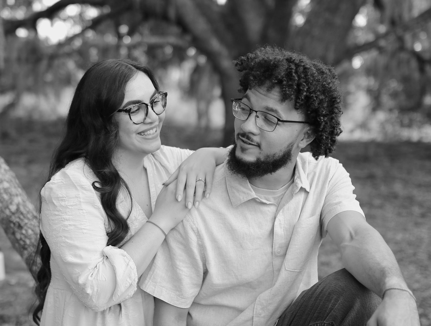 A joyful couple with curly hair share intimate moments in a series of black and white candid photos.