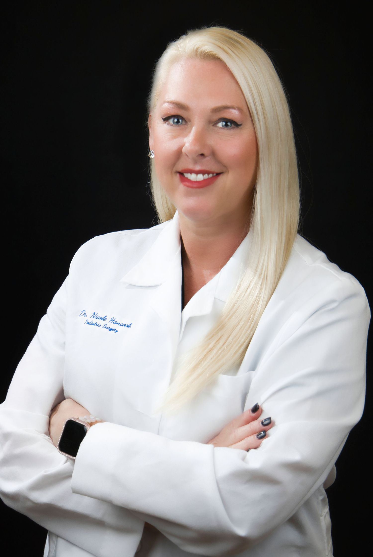 Healthcare professional in white lab coat poses for professional headshots against black background with confident smile.