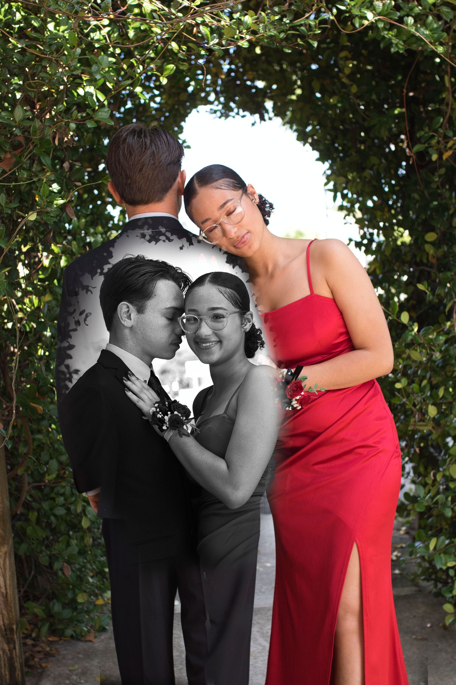 A couple shares an intimate moment outdoors in formalwear, with her wearing a red gown against a green foliage backdrop.