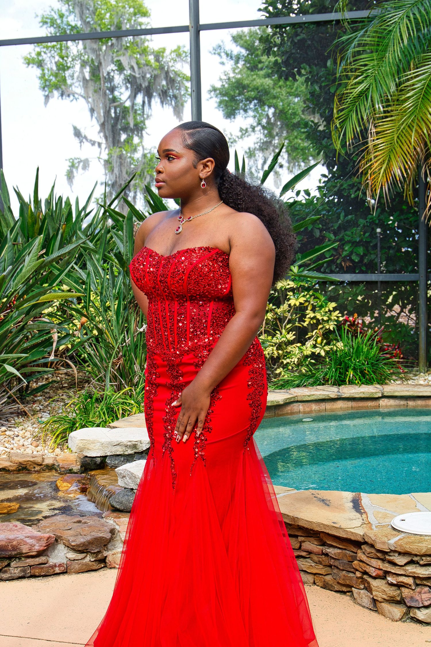 Elegant red sequined mermaid dress photographed by a luxurious poolside setting.