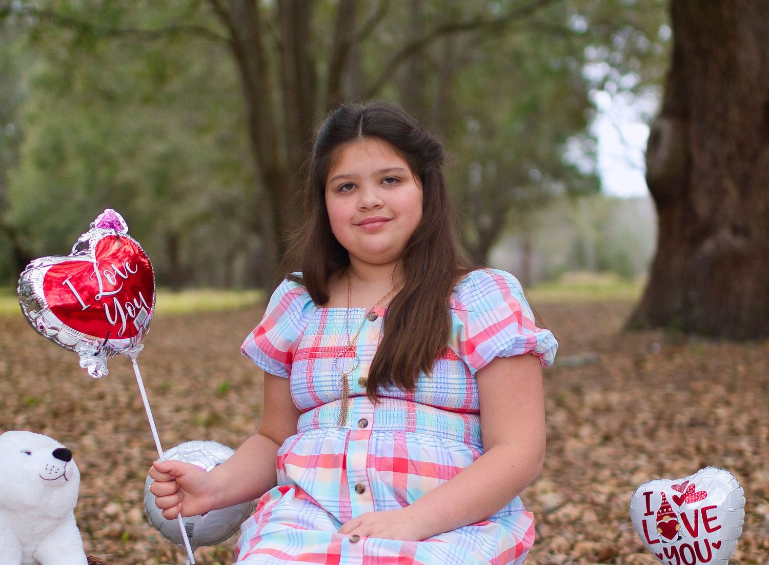 Valentine's themed portrait with heart-shaped balloon in a park setting.