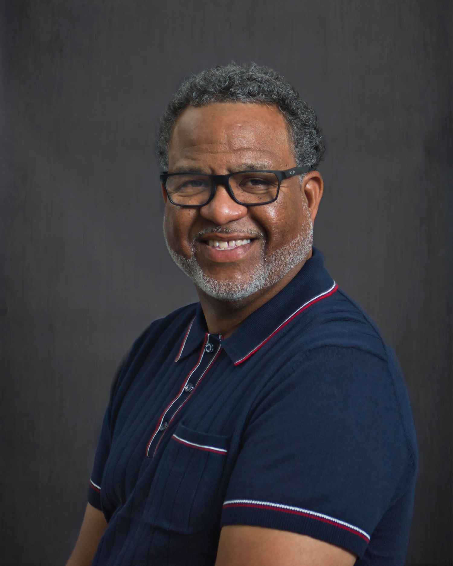 Professional studio portrait of someone in a navy polo shirt with red and white trim showing different expressions.