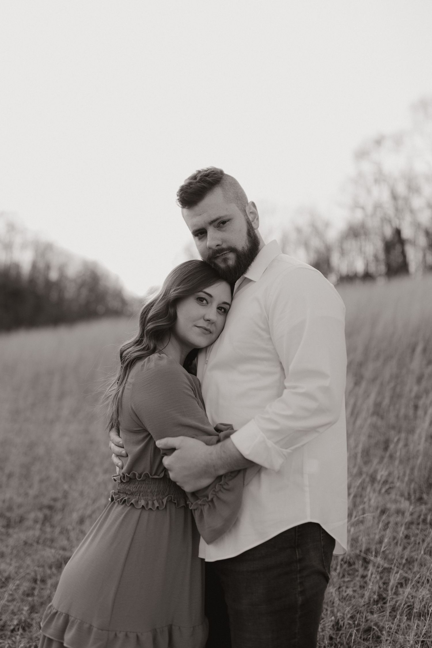 couple embraces for photo in grassy field at sunset