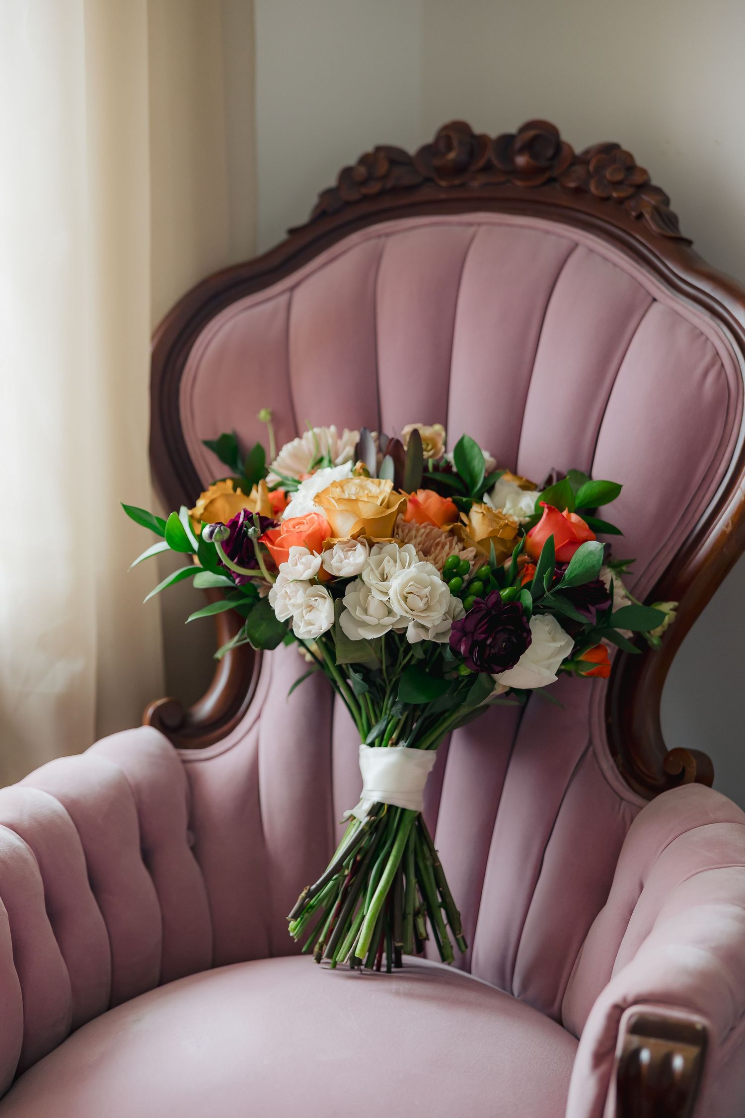 beautiful fall colored bouquet resting on a blush velvet chair