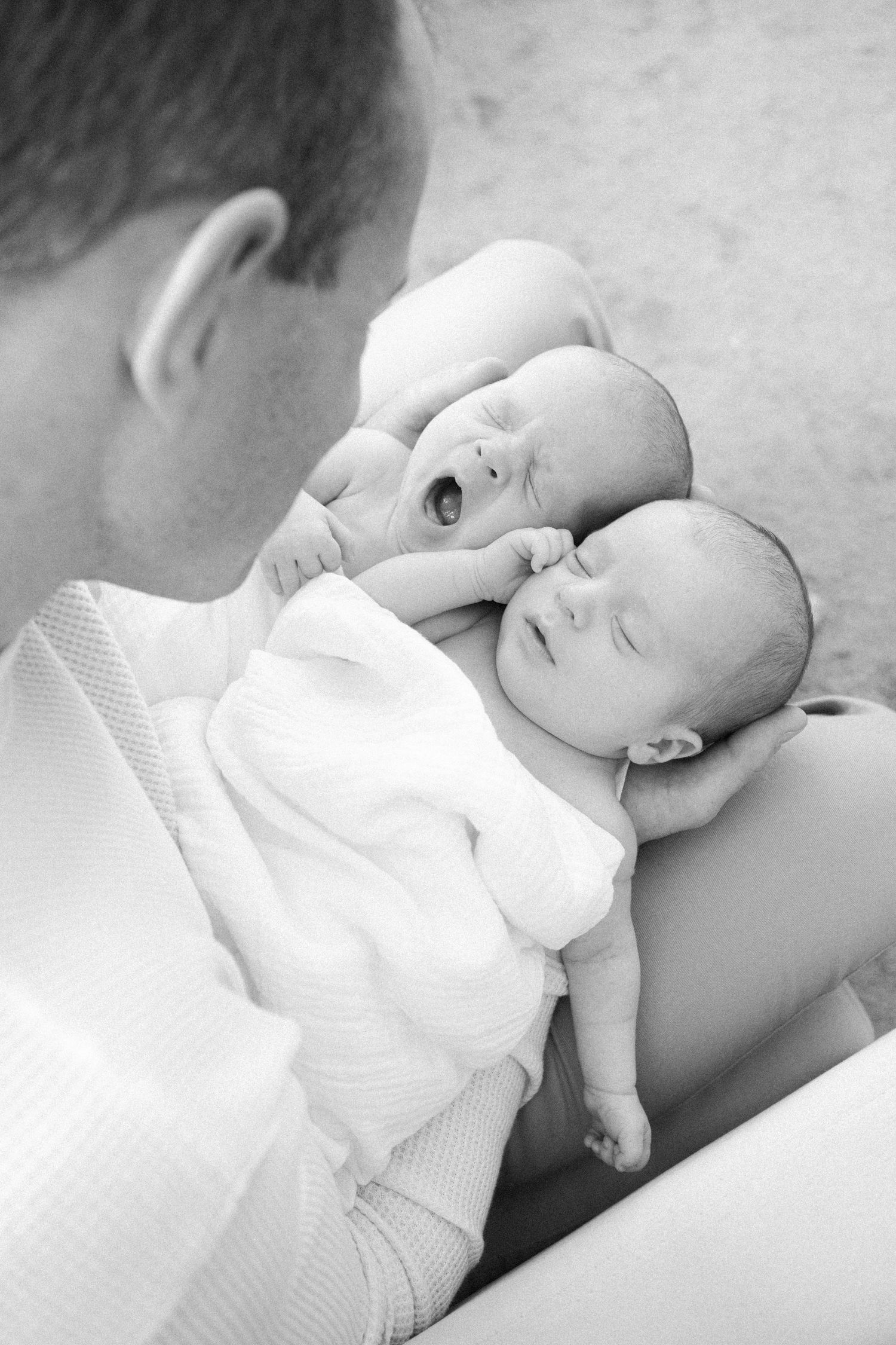 A series of black and white photos showing a baby in white clothing lying down and looking up with peaceful expressions.