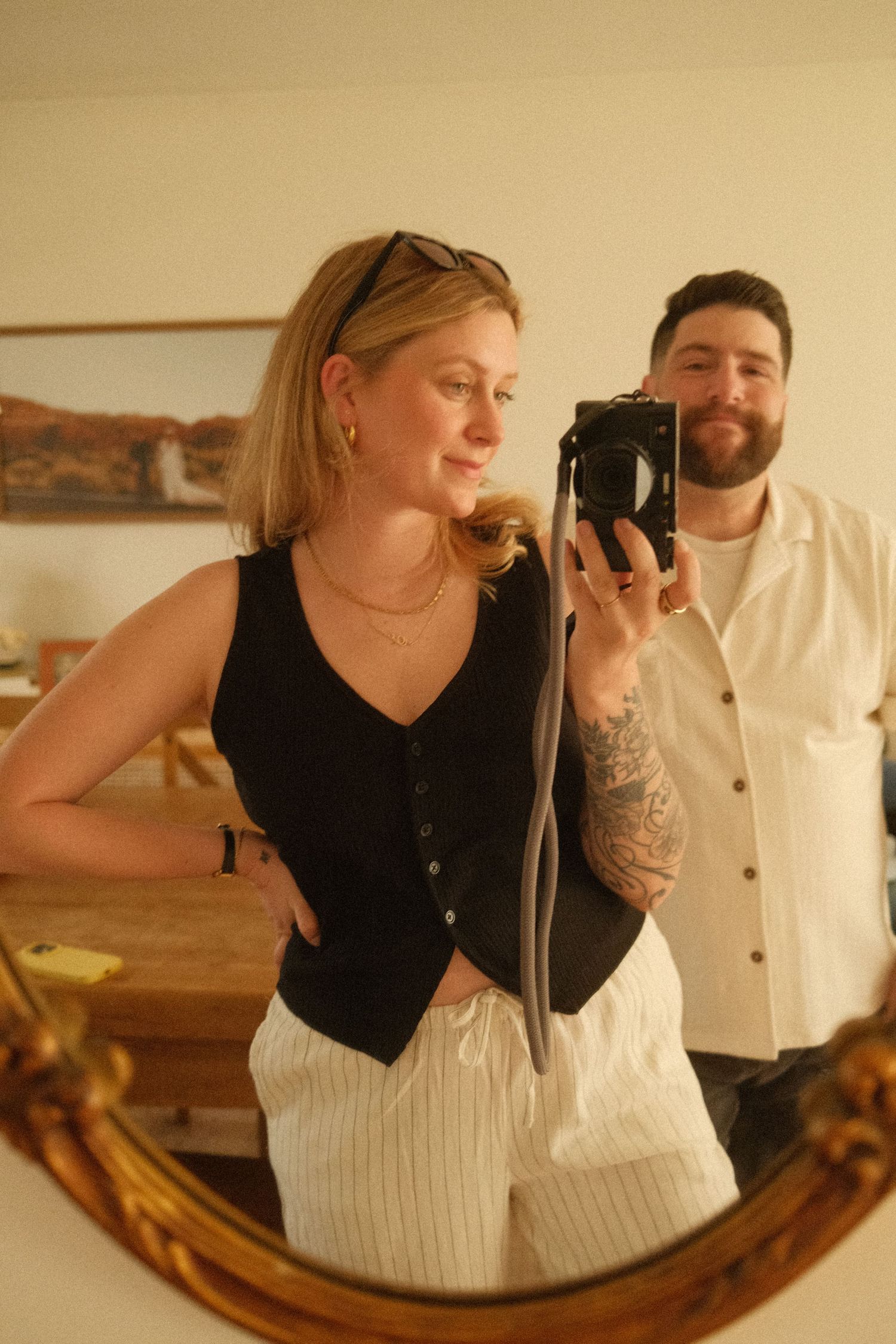 A mirror selfie shows two people in casual attire, with a black vest and white striped pants in the foreground in hunterdon county.