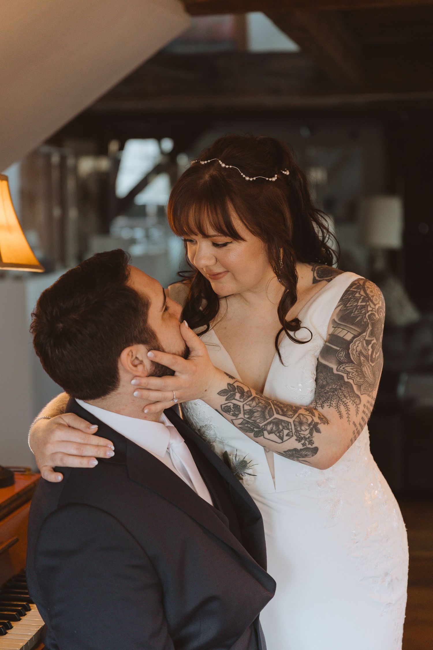 A tender moment between newlyweds sharing an intimate embrace near a piano in warm indoor lighting in hackettstown nj.