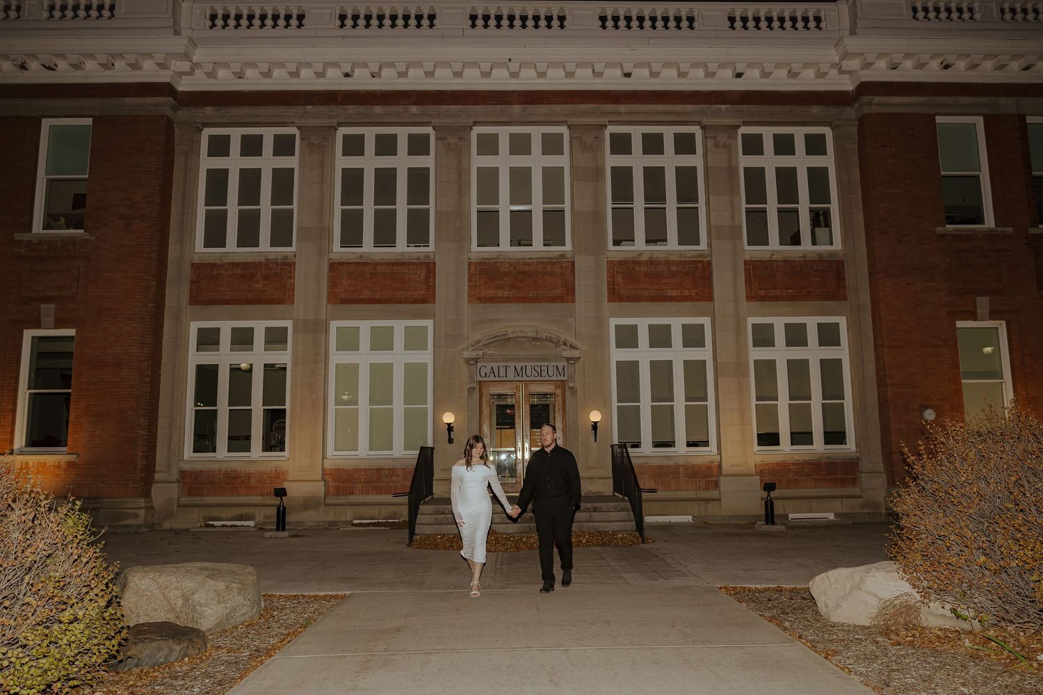 Red brick school building exterior with multiple rows of windows and students walking on campus.