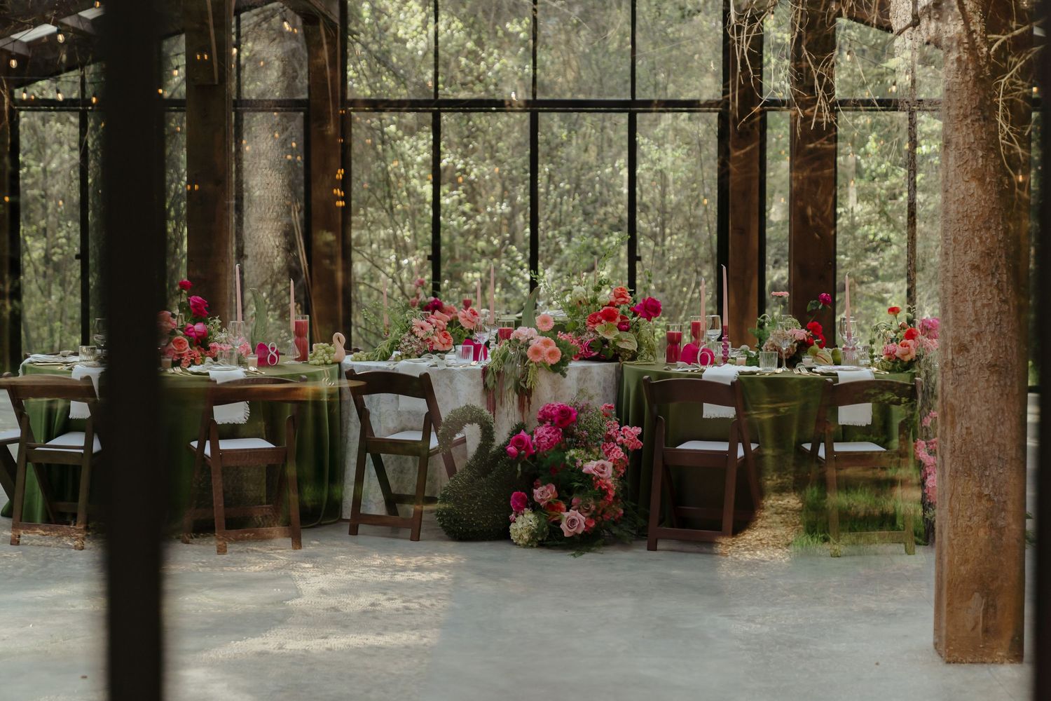 The Valley Wedding venue decorated with pink flower and surrounded by tall pine trees.