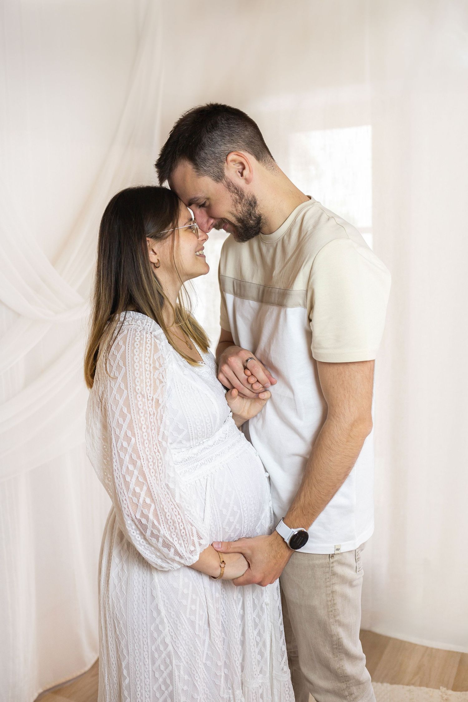Moment d'intimité d'un couple se touchant le front en studio décor bohème, shooting maternité plein de tendresse dans les Deux-Sèvres.