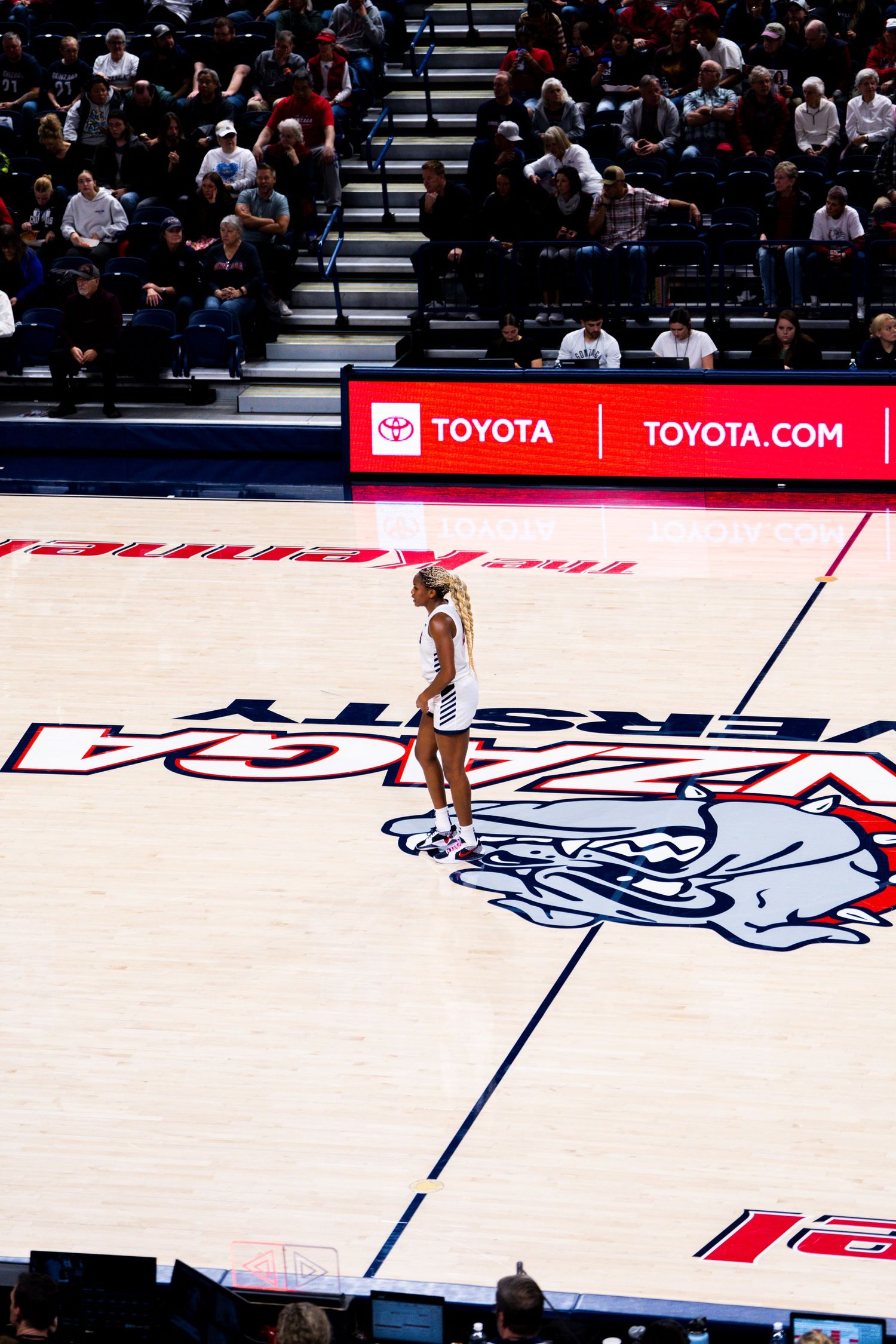 A basketball player stands on the USA team logo on a court with Toyota advertisement banners visible in the background.