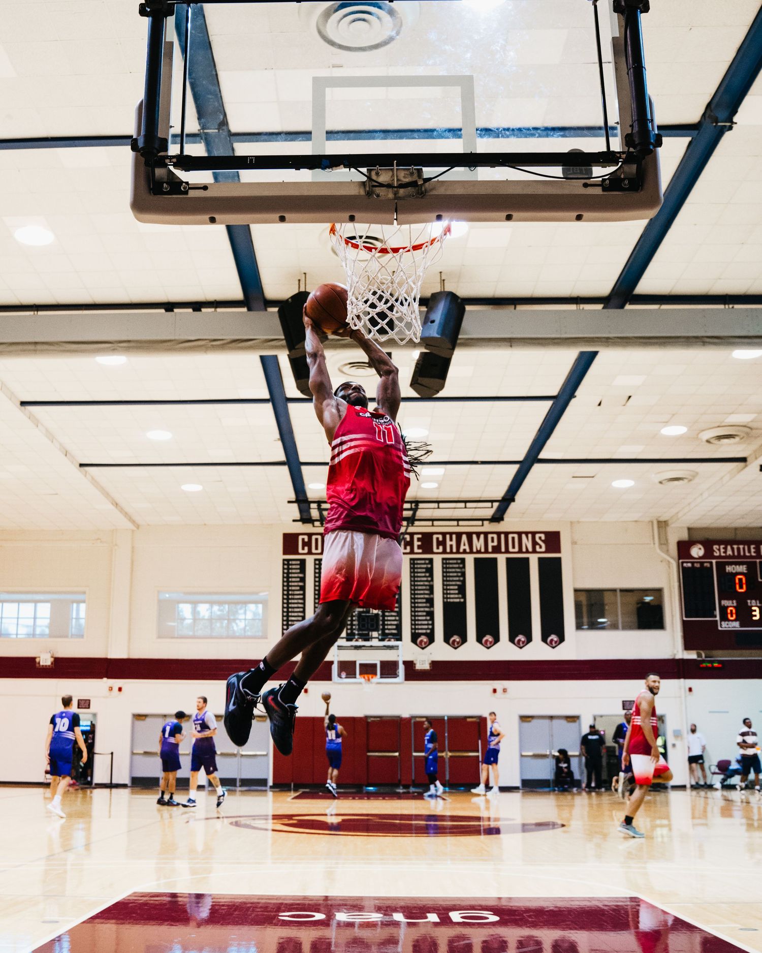 A sequence of basketball players performing slam dunks on an indoor court during practice or training.