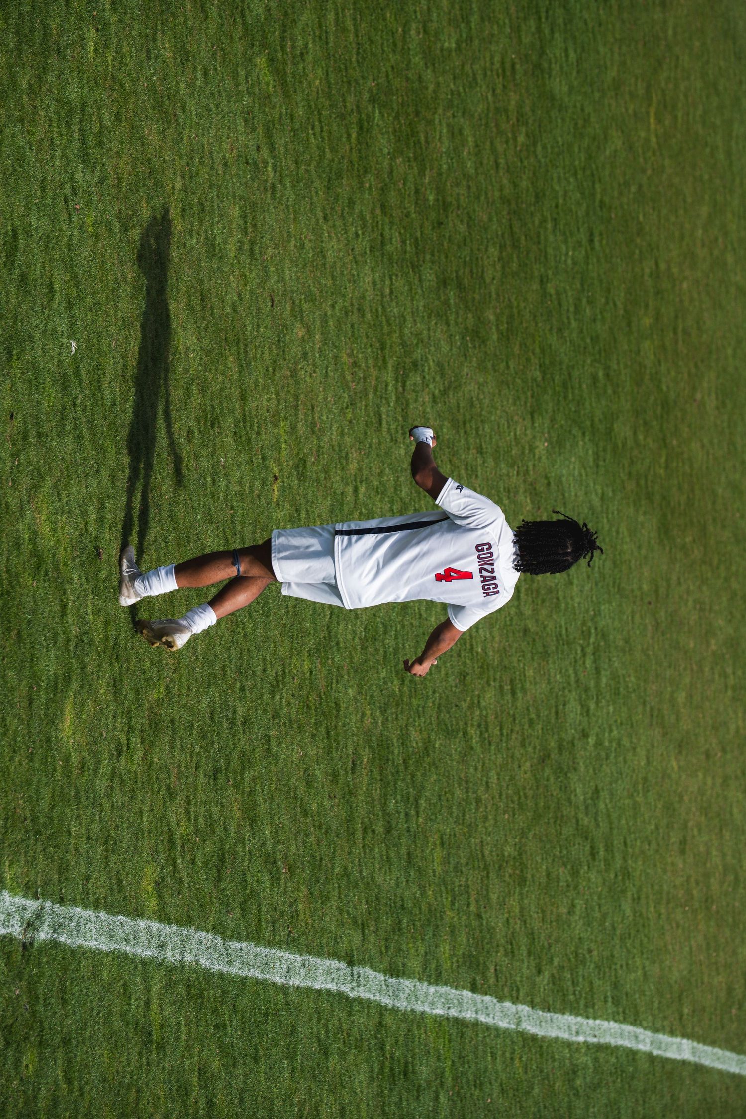 Soccer player lying down on green grass field next to white boundary line during match.