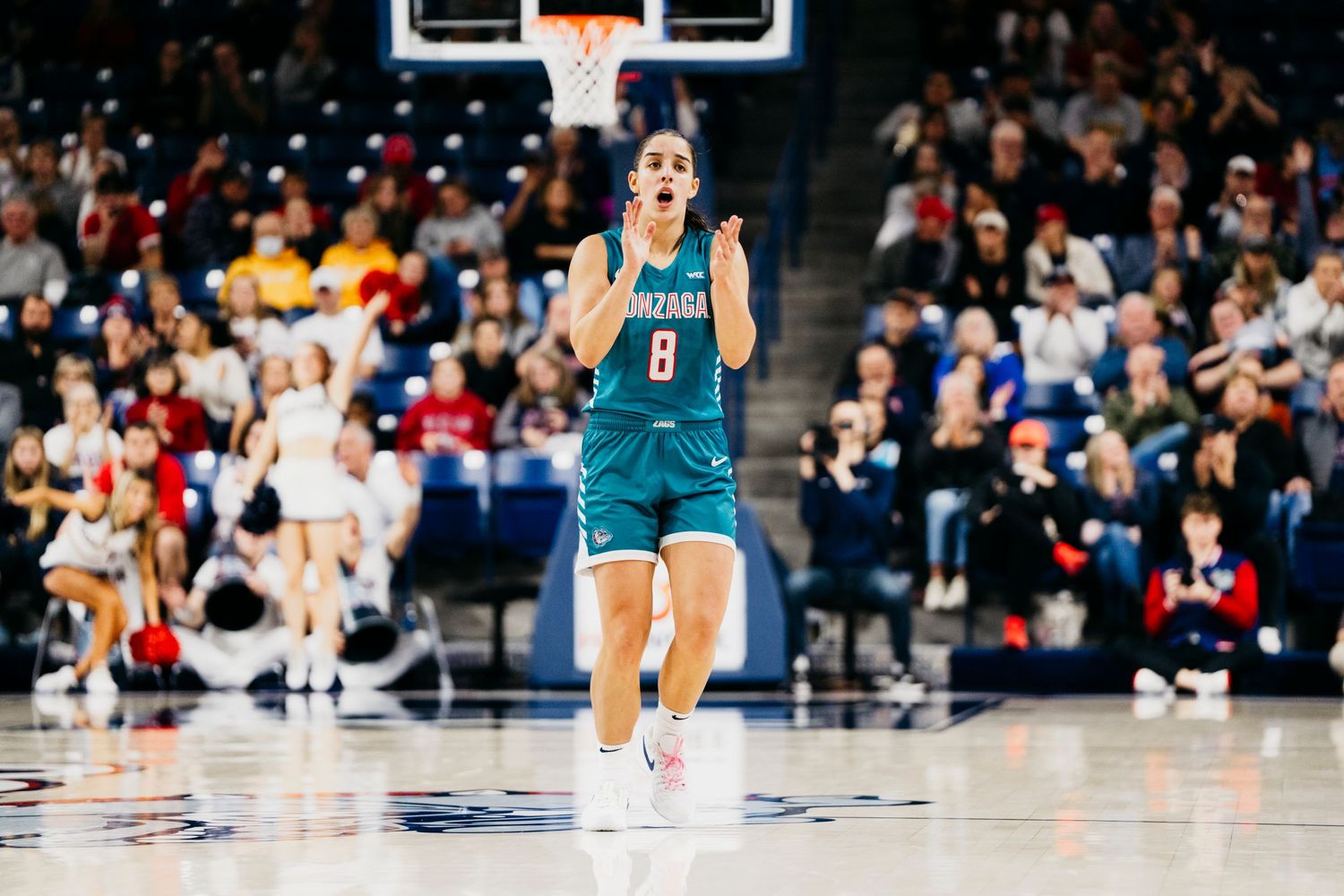 A basketball player in a teal uniform celebrates on the court during a professional game.