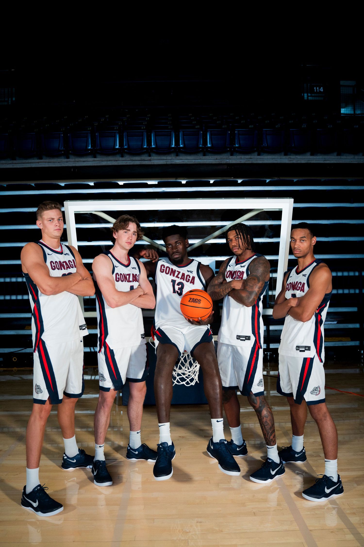 Basketball team members in UConn uniforms pose together on a court for a group photo during practice.