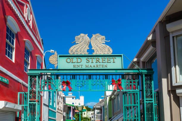 Colorful entrance gate to Old Street in Sint Maarten with ornate green metalwork and lion sculptures under a bright blue sky.