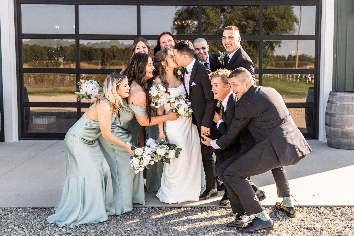 Wedding party members celebrate and dance together in a fun group moment outside a modern venue.