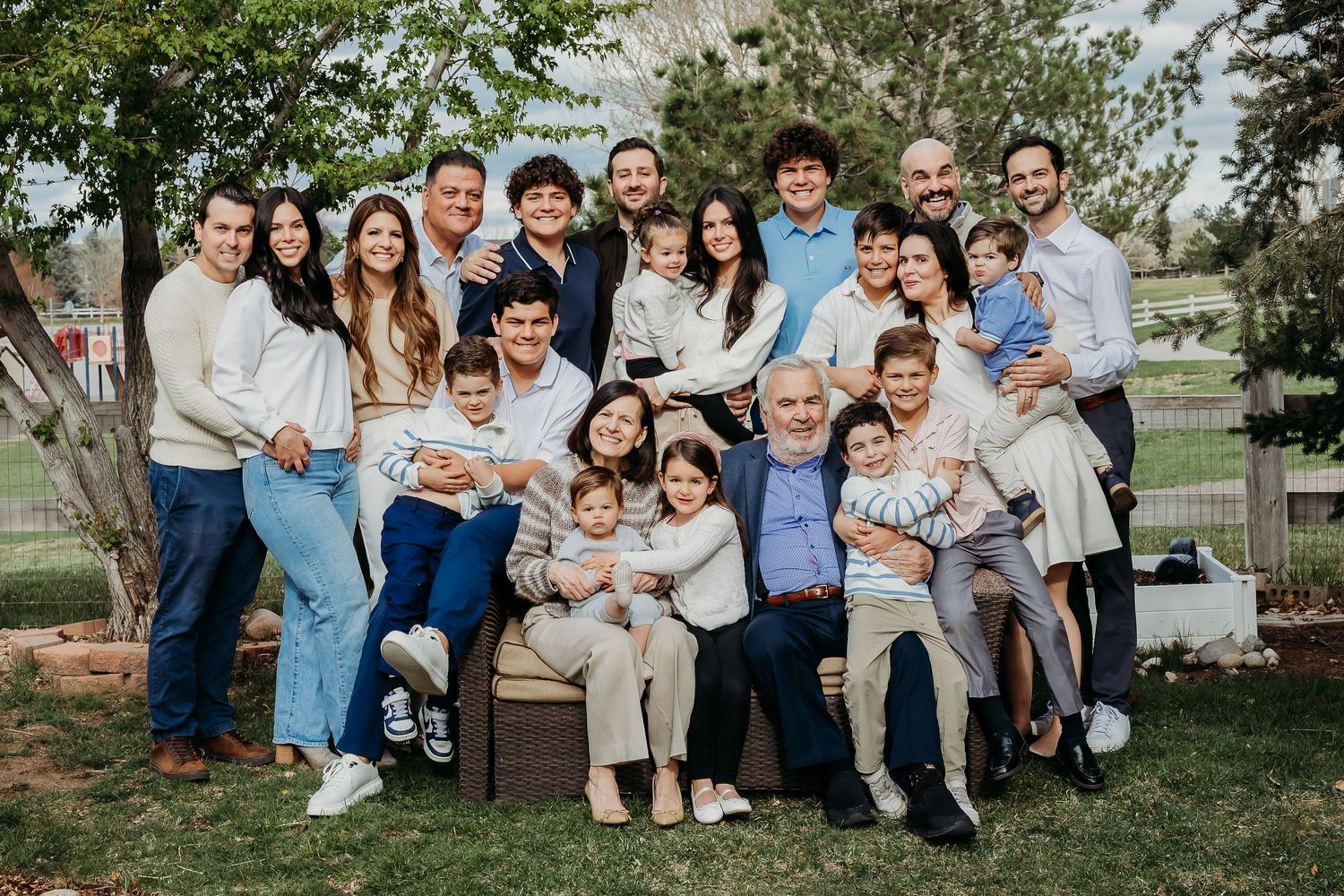 Extended family gathering outdoors for a group photo session in a park setting.
