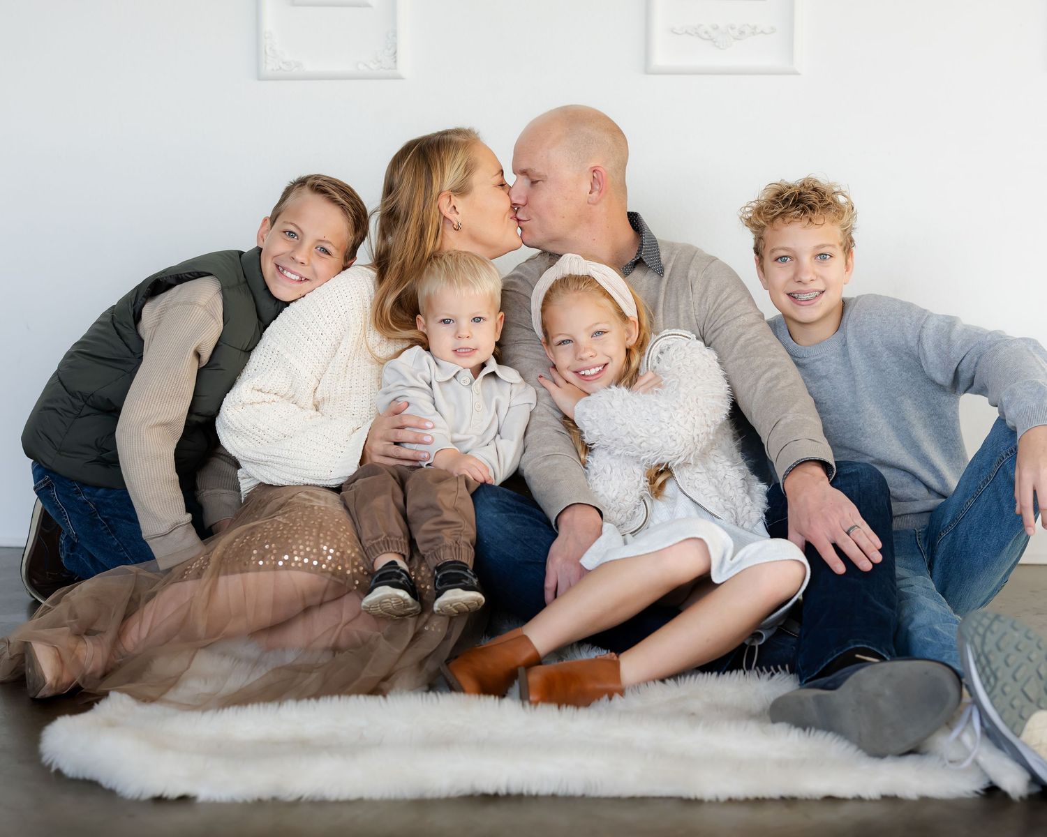 A casual family photoshoot on a white couch showing playful interaction.