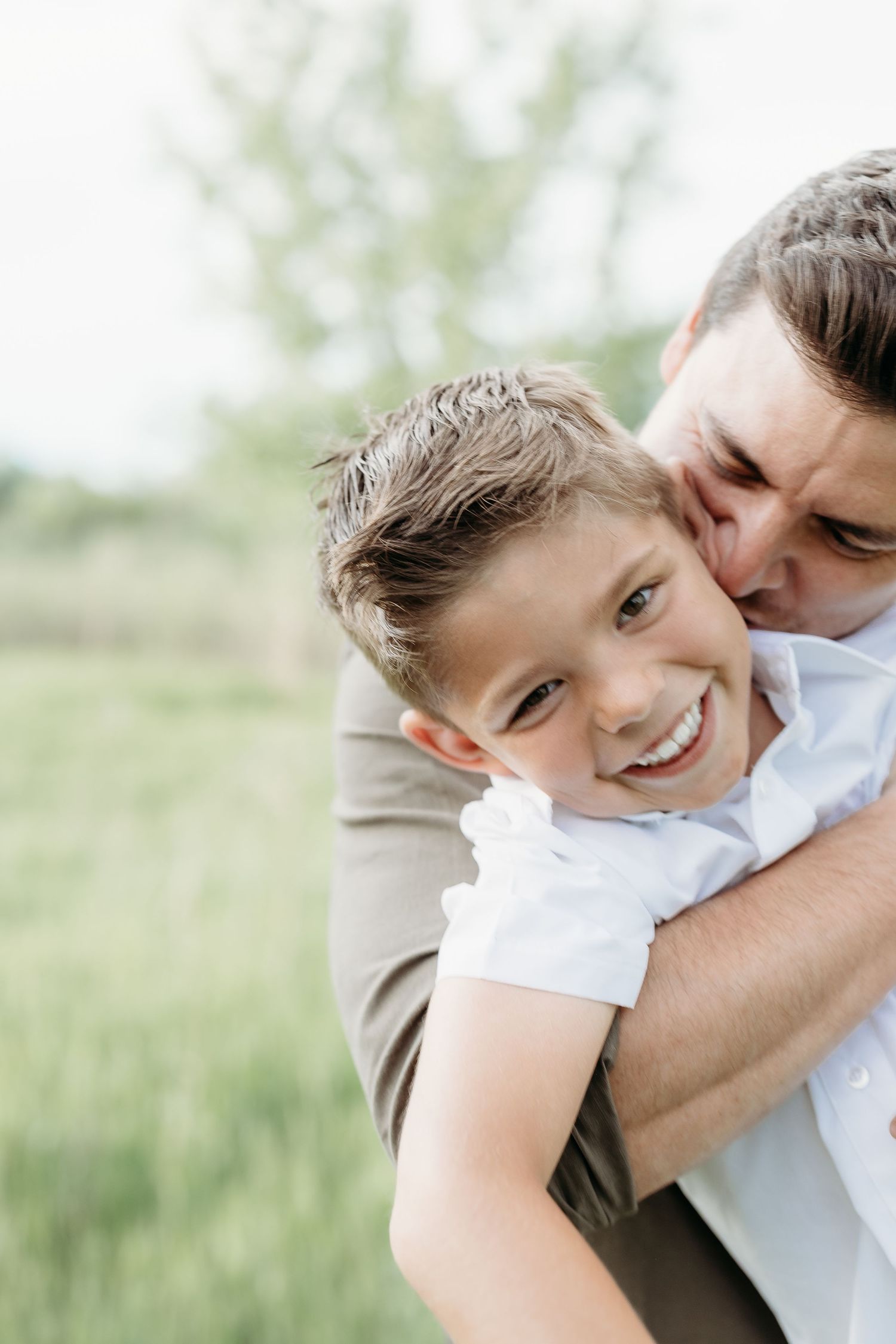 Joyful moment captured in outdoor portrait against soft green background.