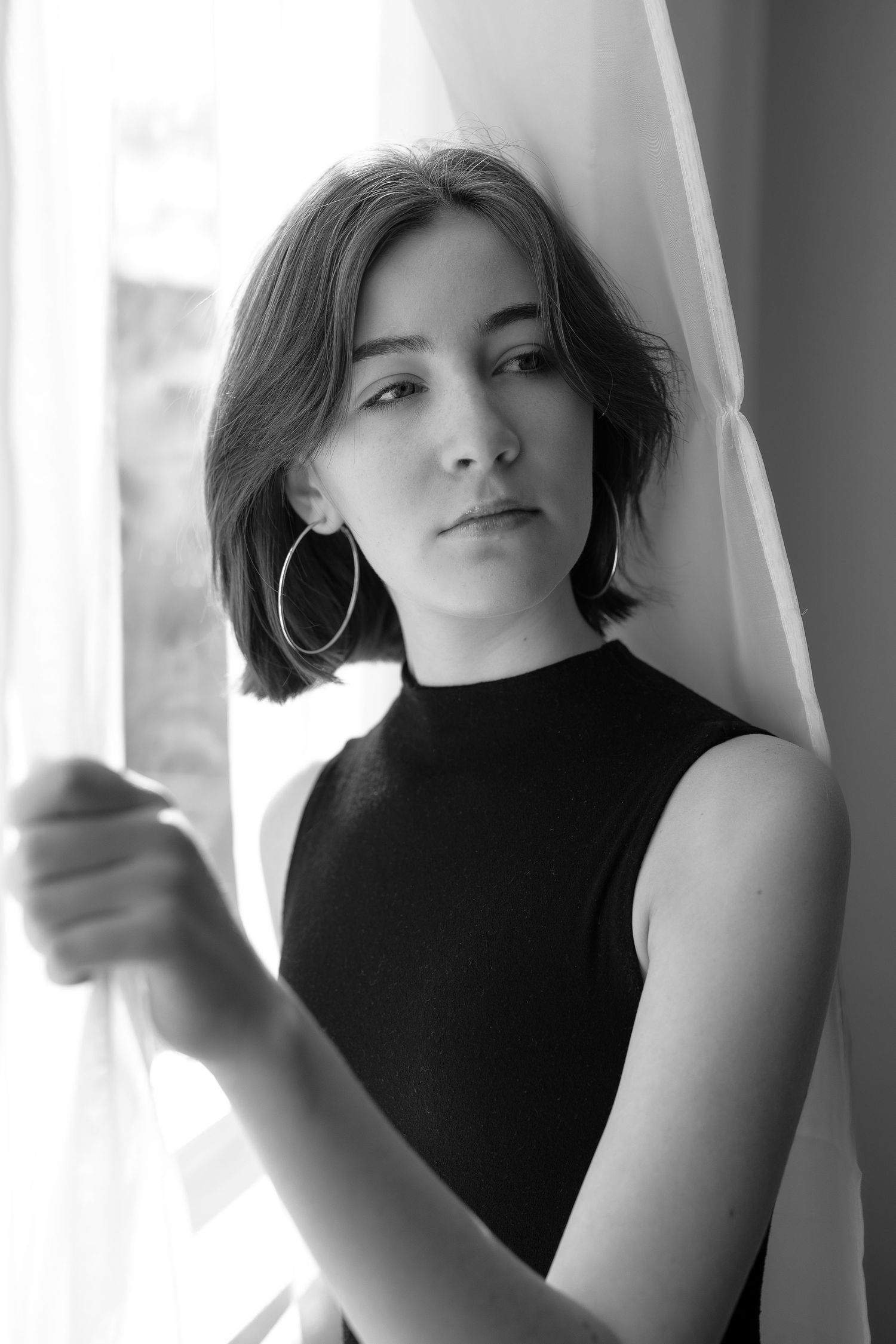 8th grade girl in Black and white portrait of someone in a sleeveless black top posing against a light background.