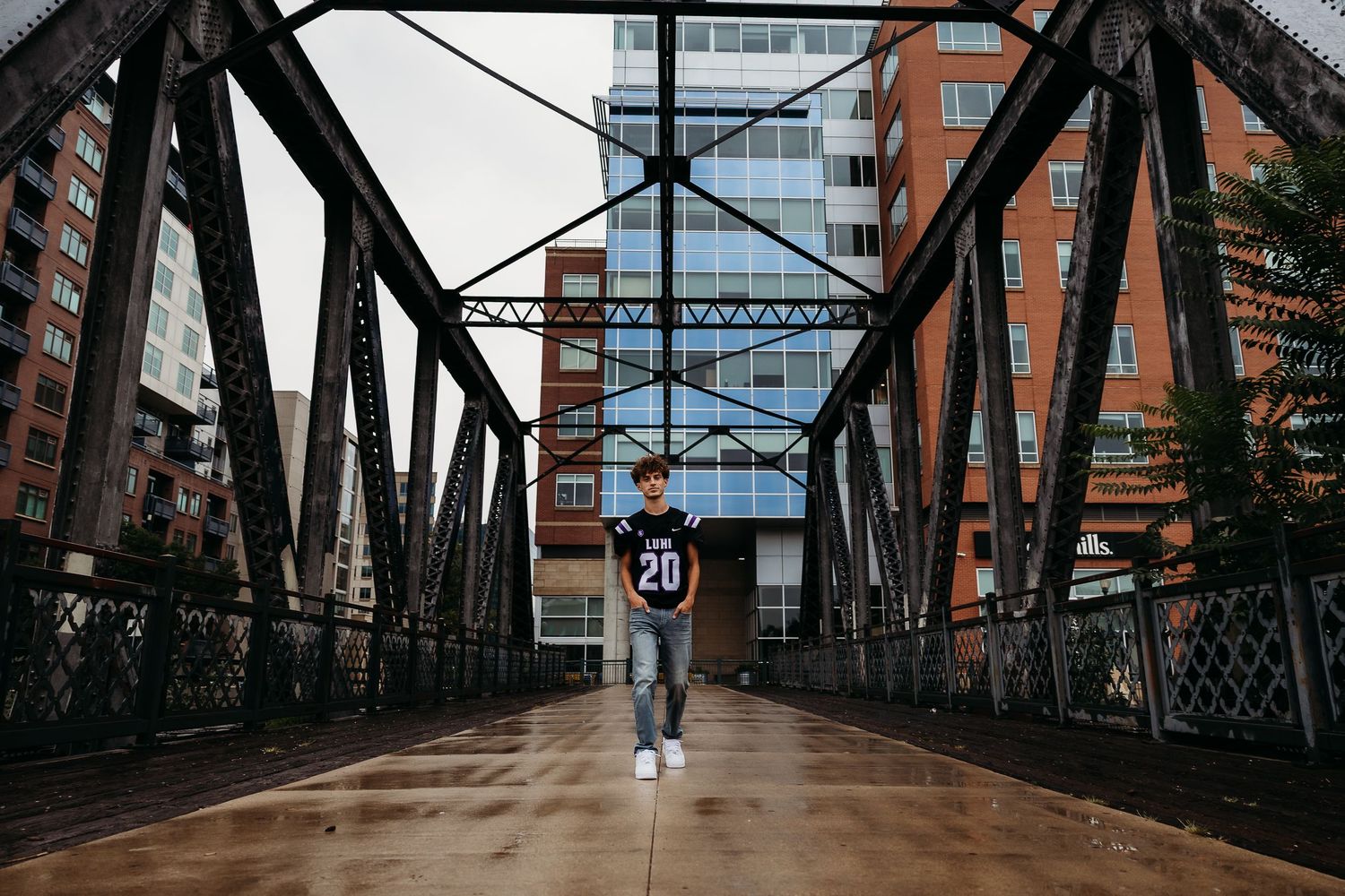Person walking on industrial metal bridge with urban buildings in background.