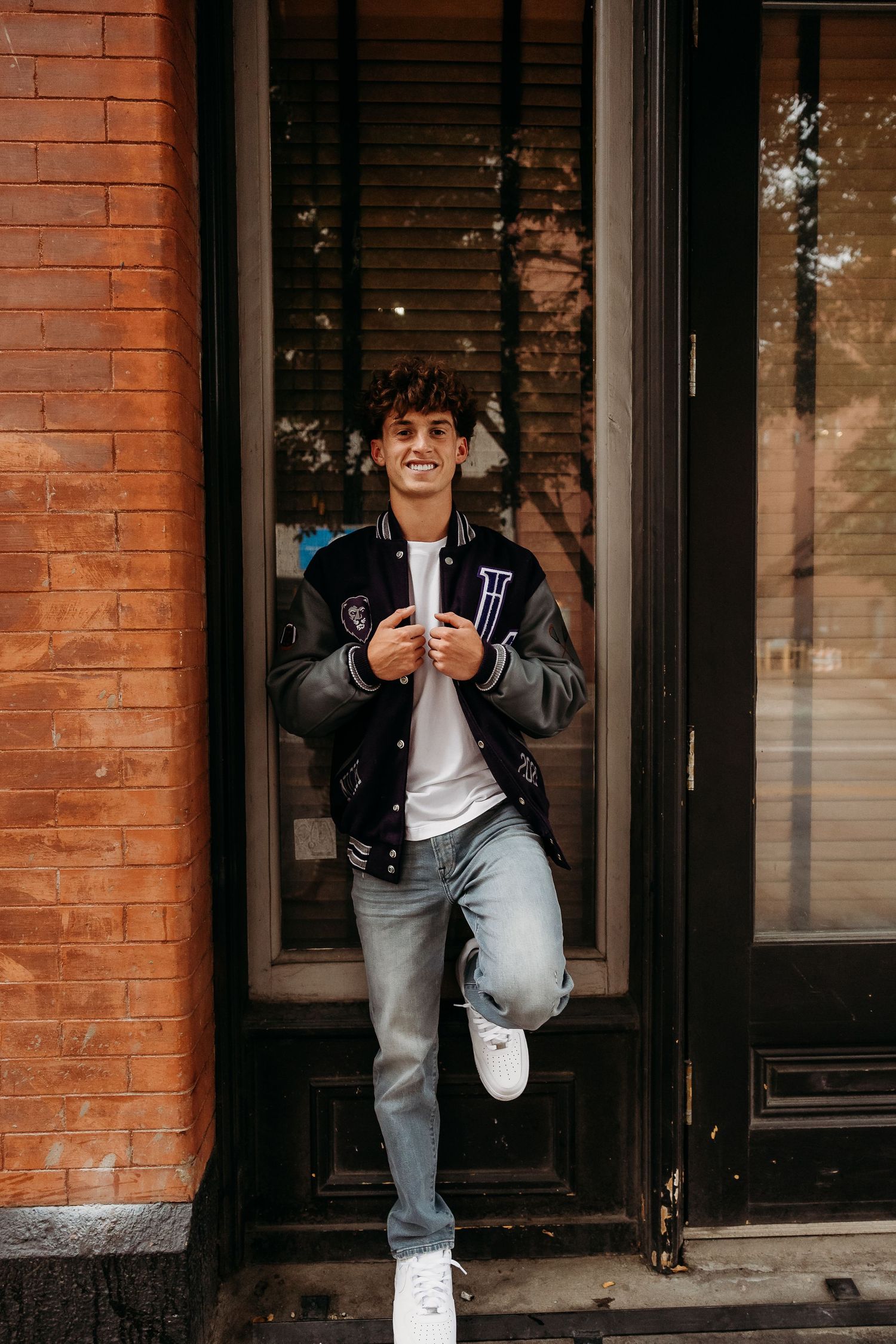 Urban portrait session against orange brick building with black doorway.
