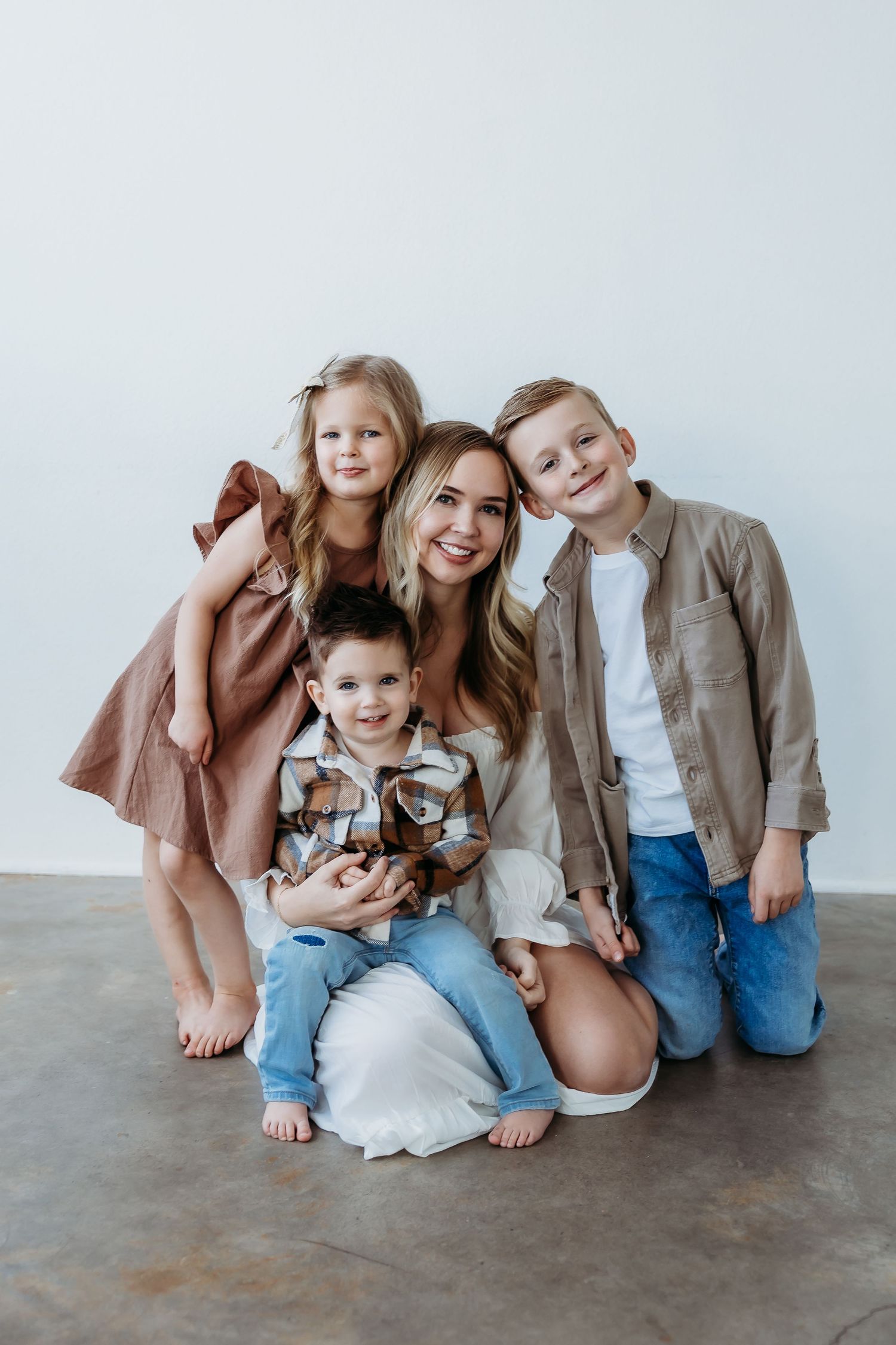 A group of children sit together on a concrete floor wearing casual clothing in a series of candid poses.
