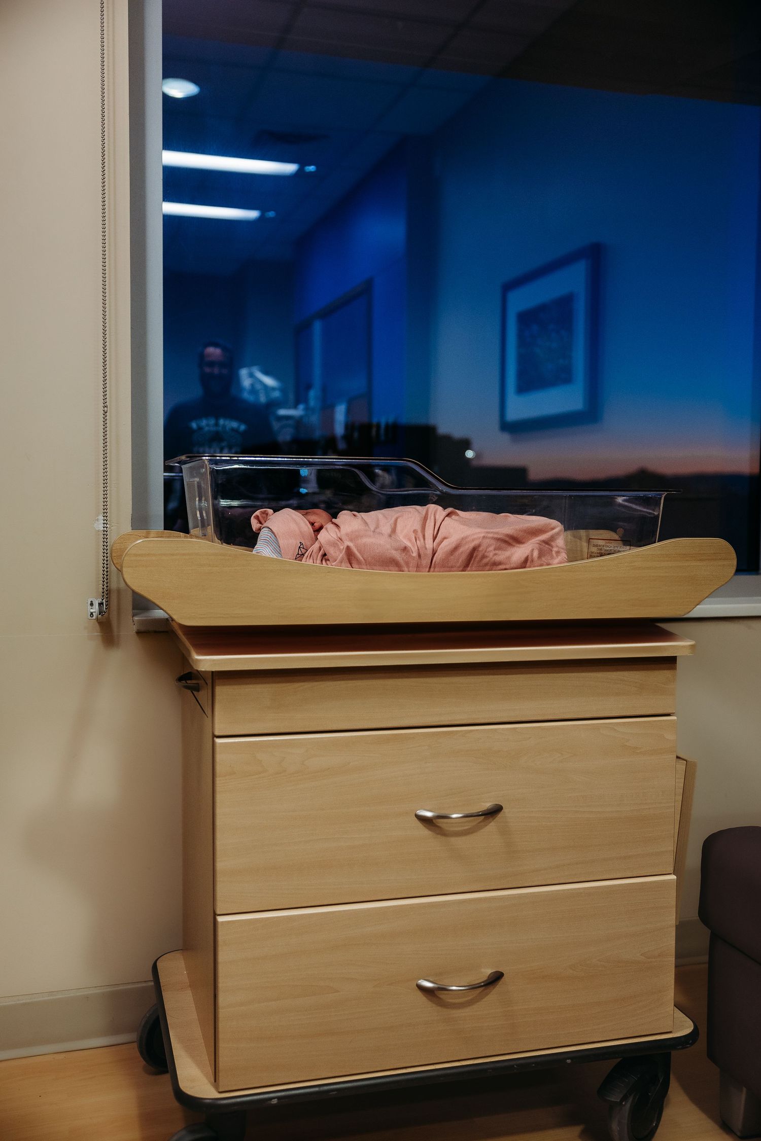 Wooden dresser against wall in room with blue evening light through window.