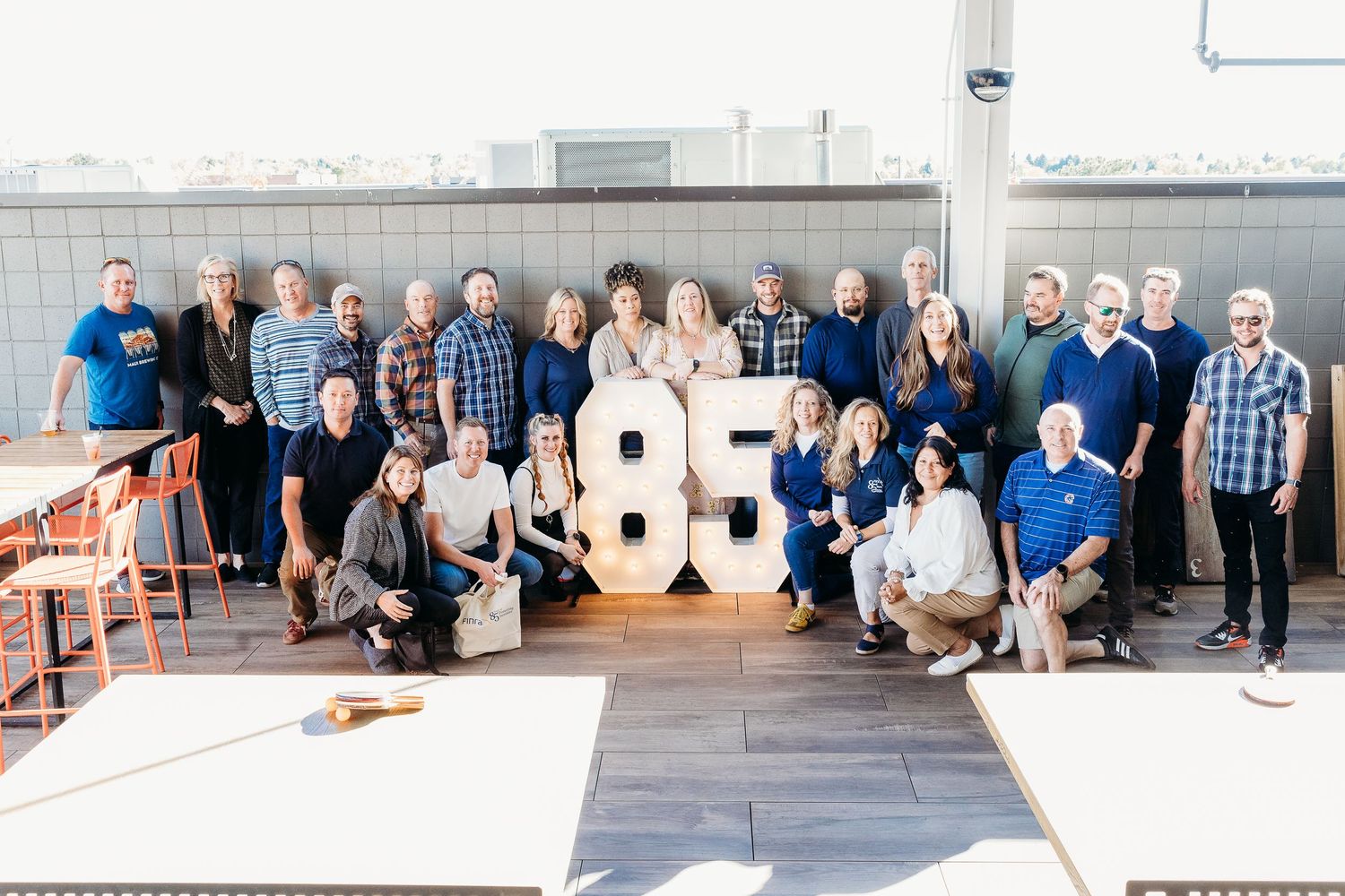 Group photo session against white wall with large decorative numbers.
