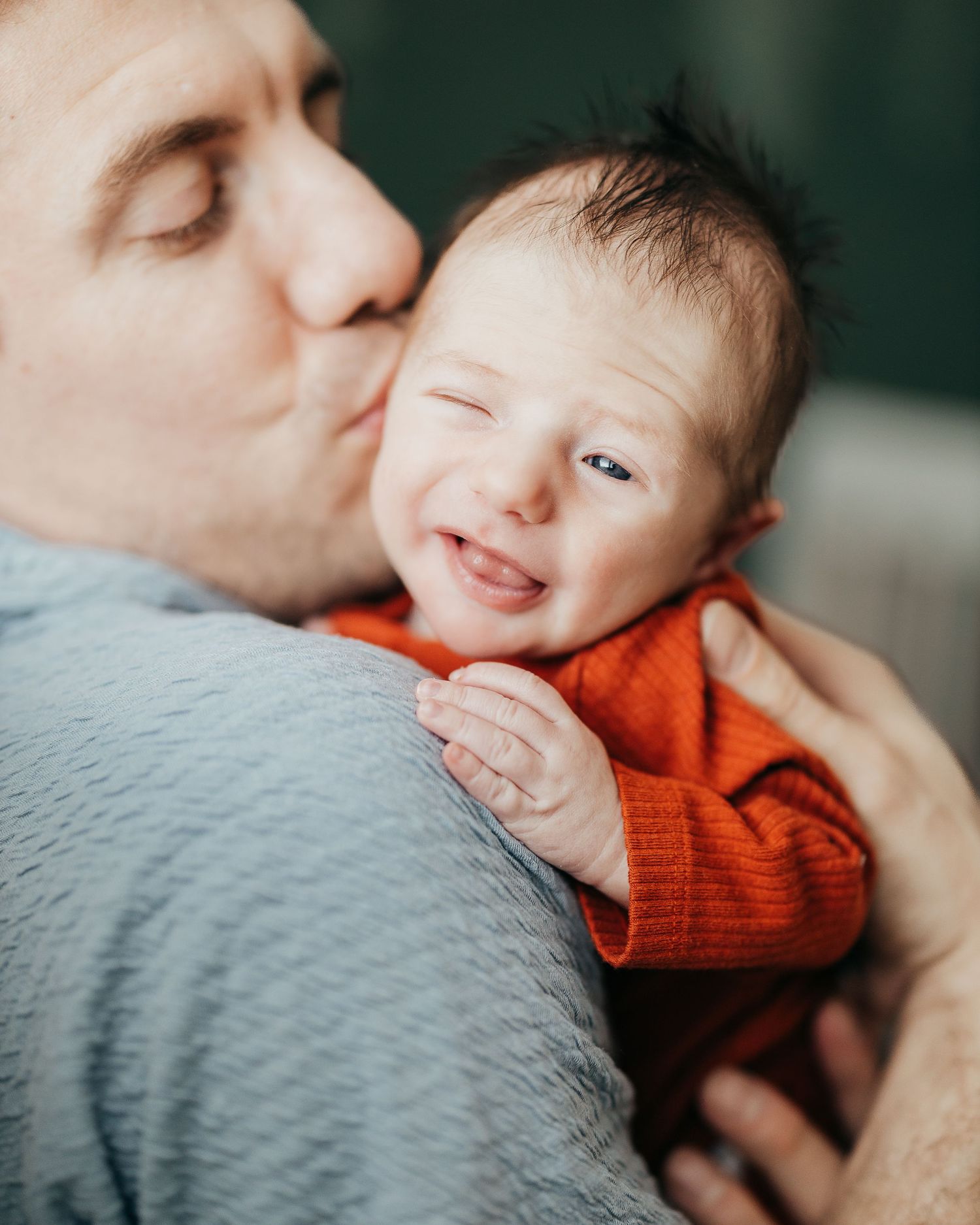 Close-up of tender moment with baby wearing orange sweater.