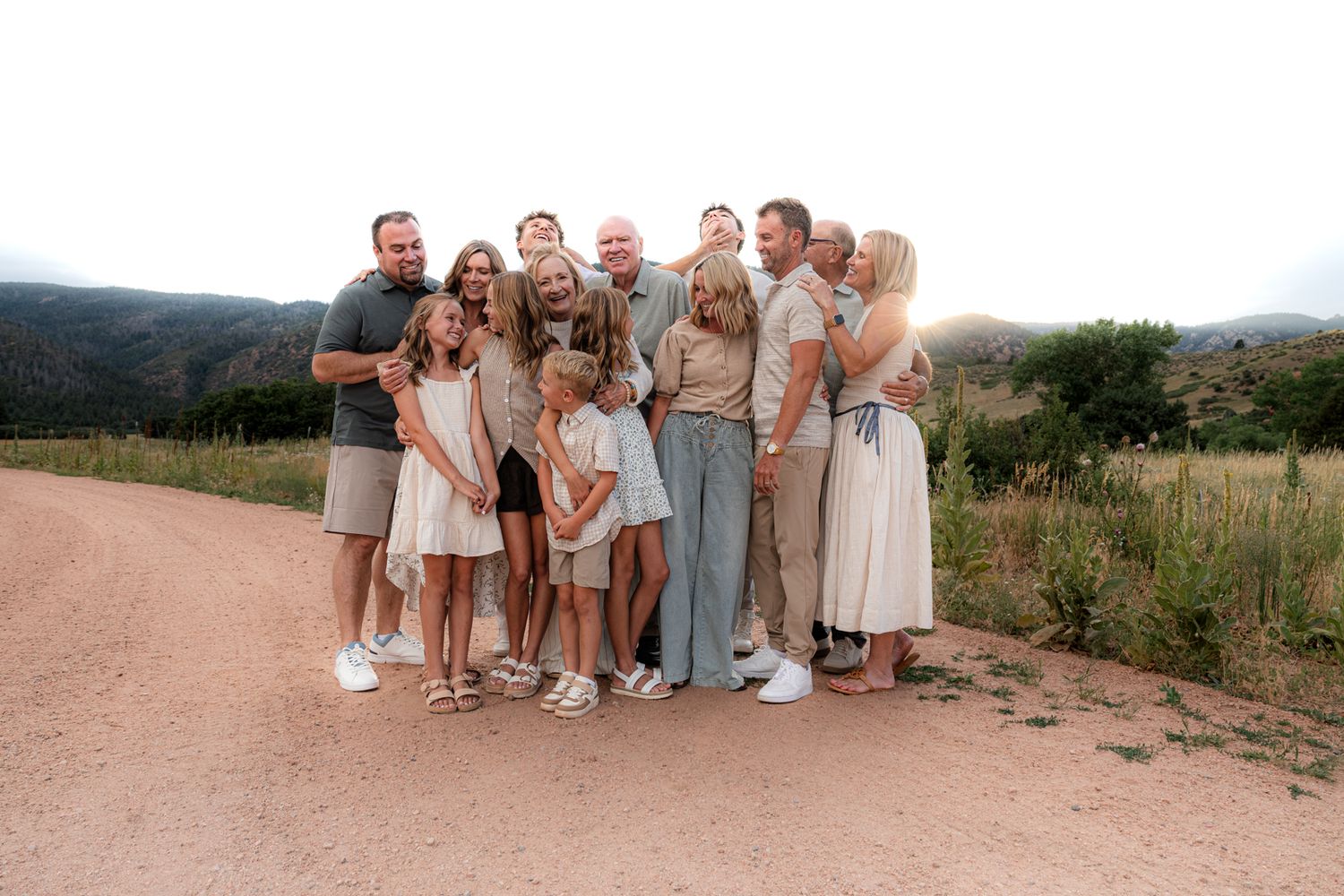 Extended family portrait on a mountain trail at golden hour wearing coordinated neutral outfits.