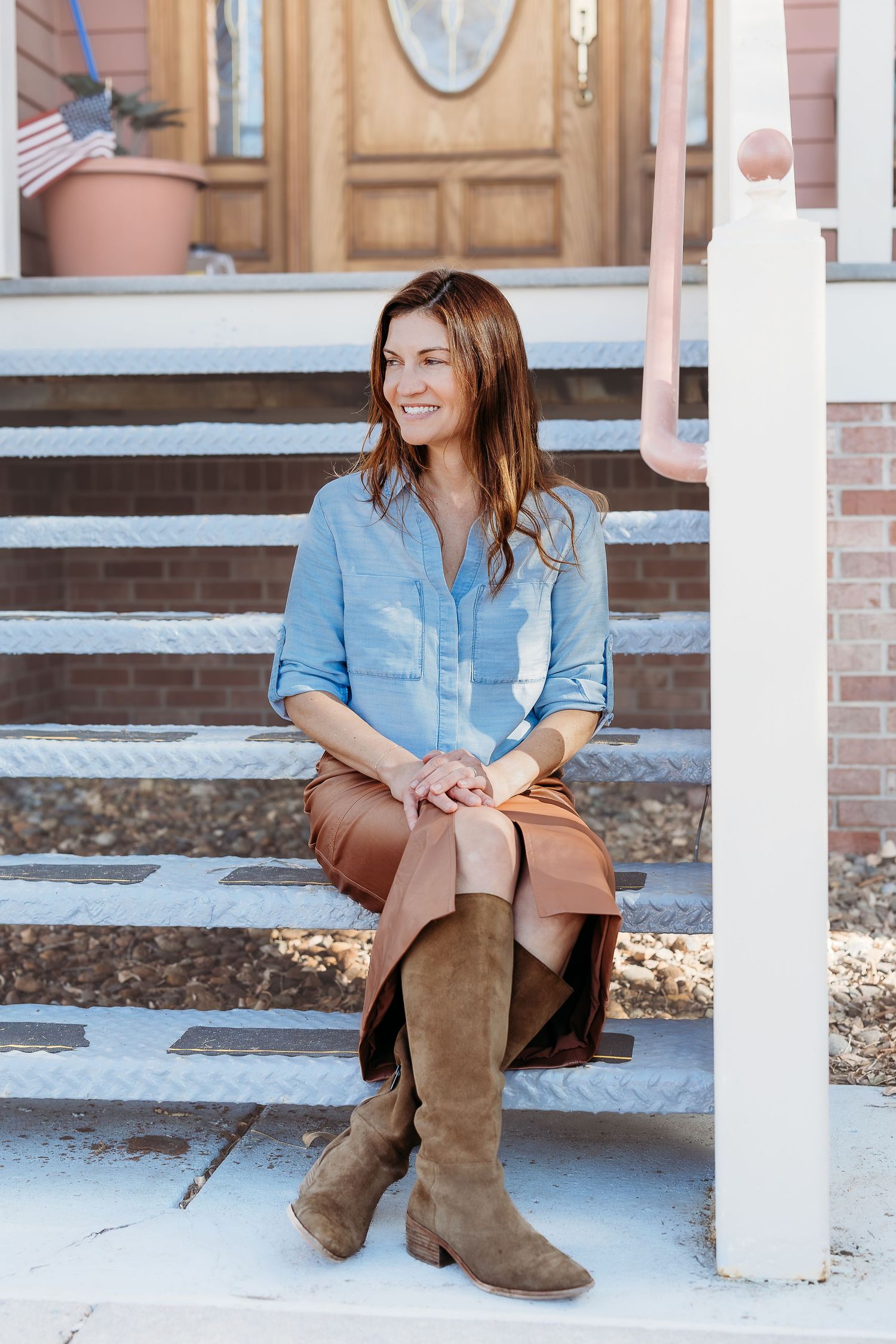 Lifestyle portrait series on brick steps wearing blue shirt and brown boots.