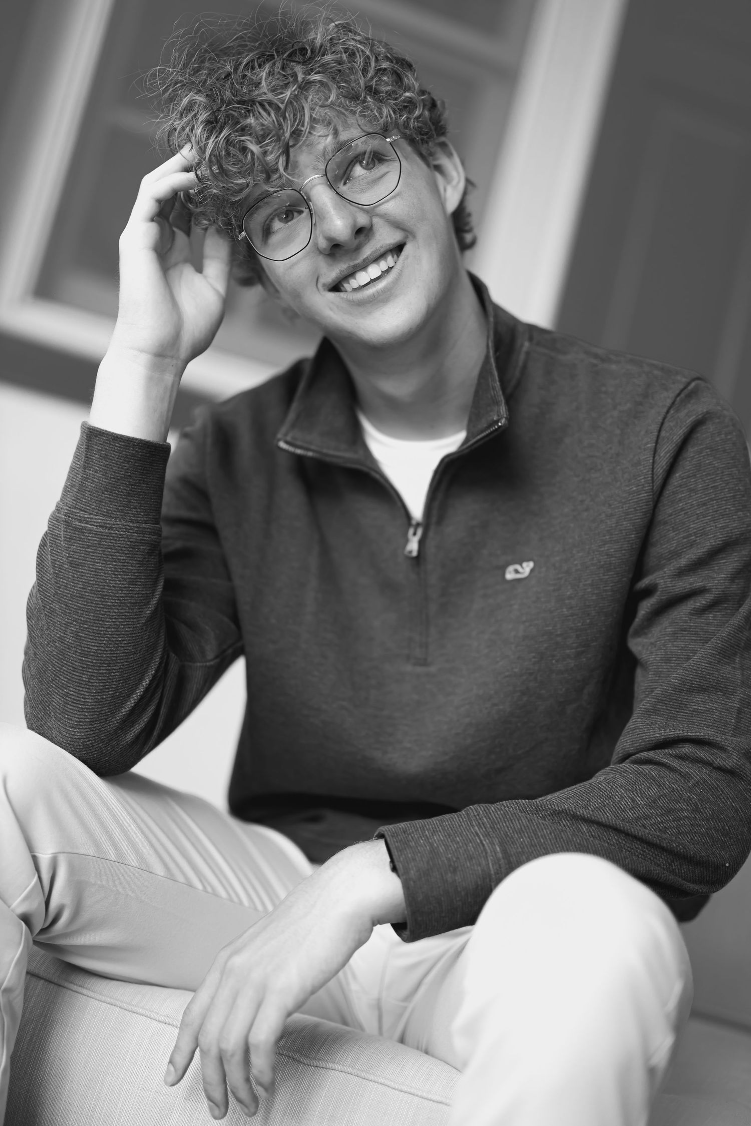 Black and white portrait showing relaxed pose in quarter-zip sweater.