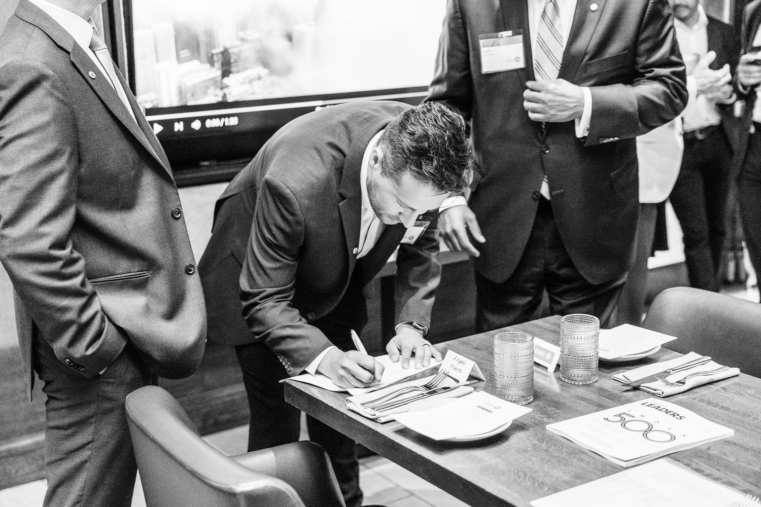 Business meeting participants signing documents at conference table.