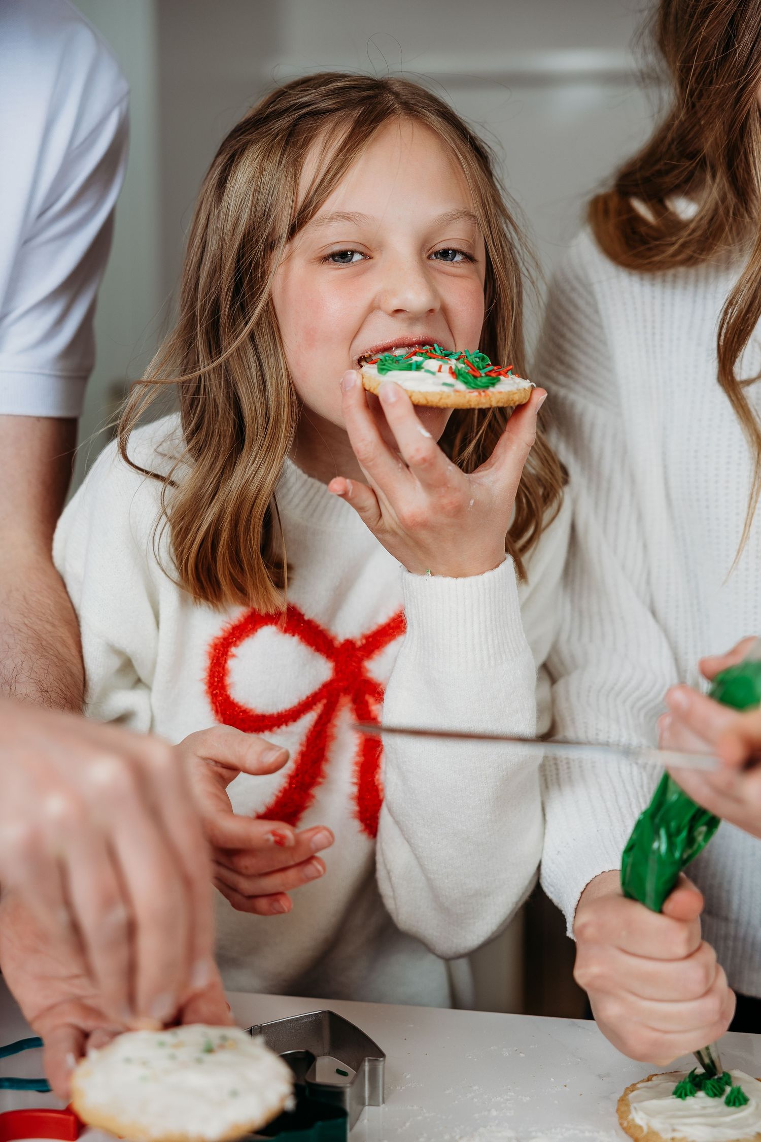 Close-up shots of cookie decorating with Christmas-themed frosting and sprinkles.