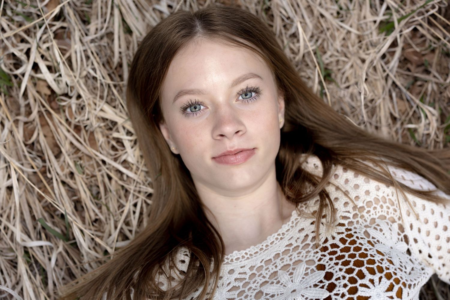 Portrait series showing woman with long brown hair lying against textured backdrop.