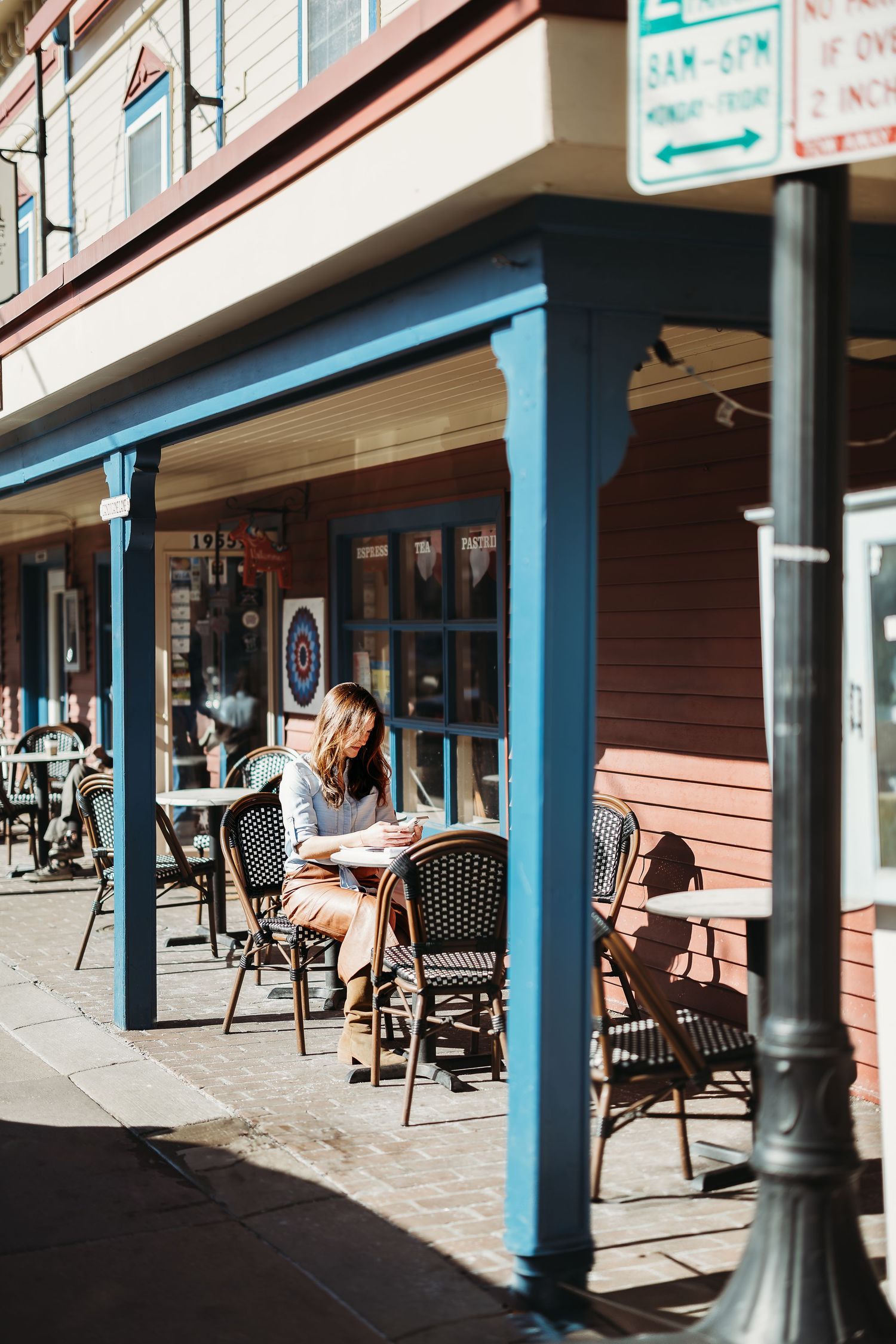 Exterior storefront with covered porch area featuring rocking chairs and columns.