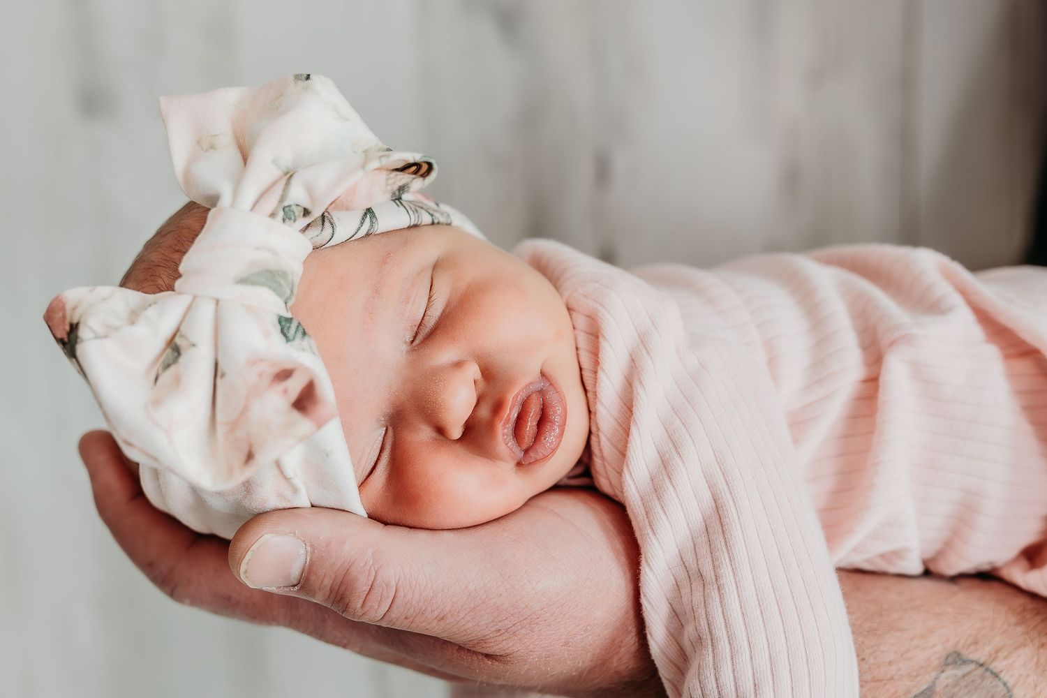 Sleeping newborn wrapped in pink swaddle blanket.