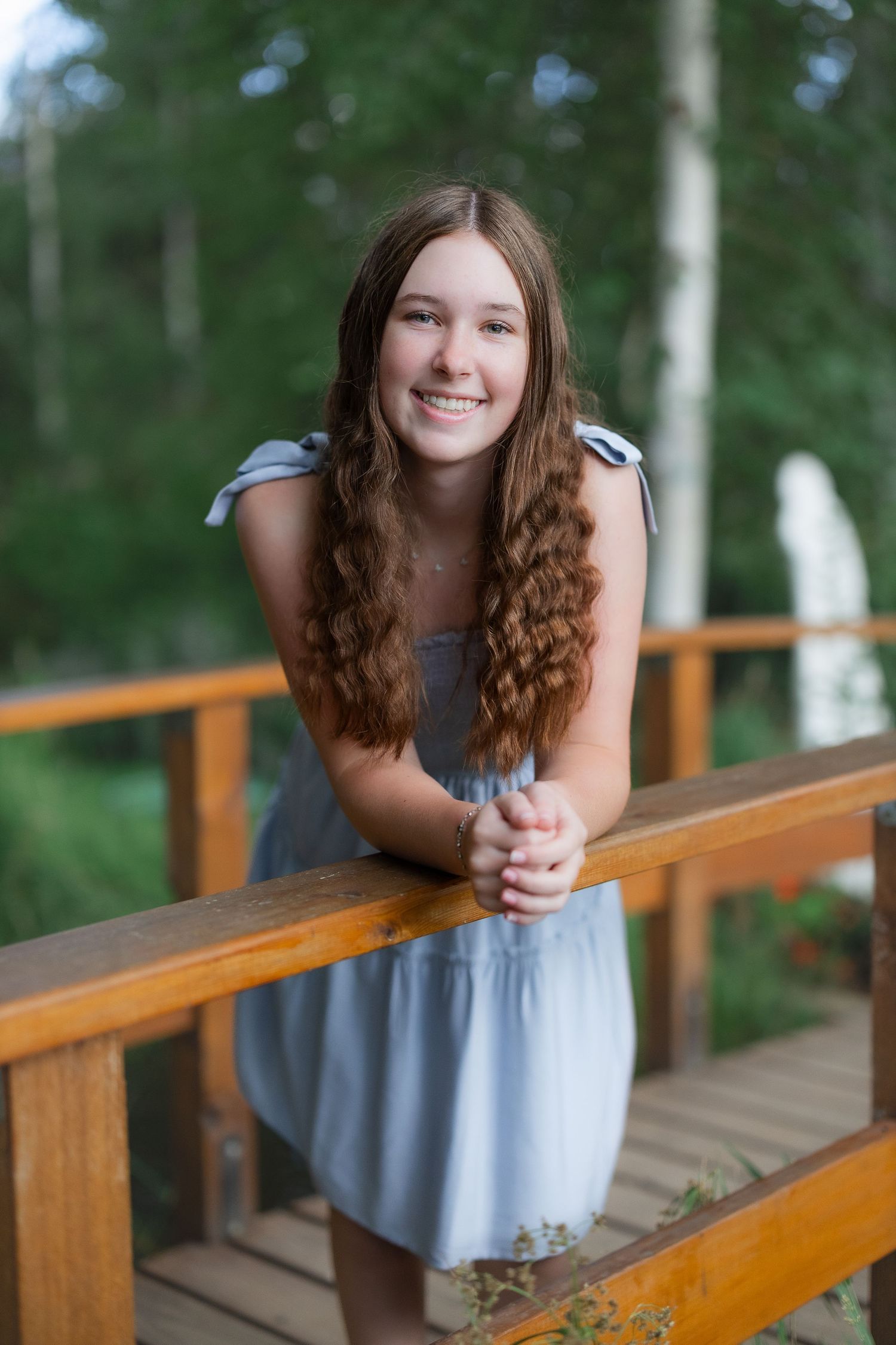 Portrait on wooden deck railing with forest backdrop.